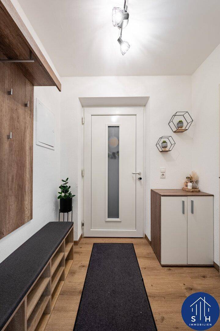 Eingangsbereich mit Garderobe, Sitzbank mit Schuhregal und einer modernen Kommode.