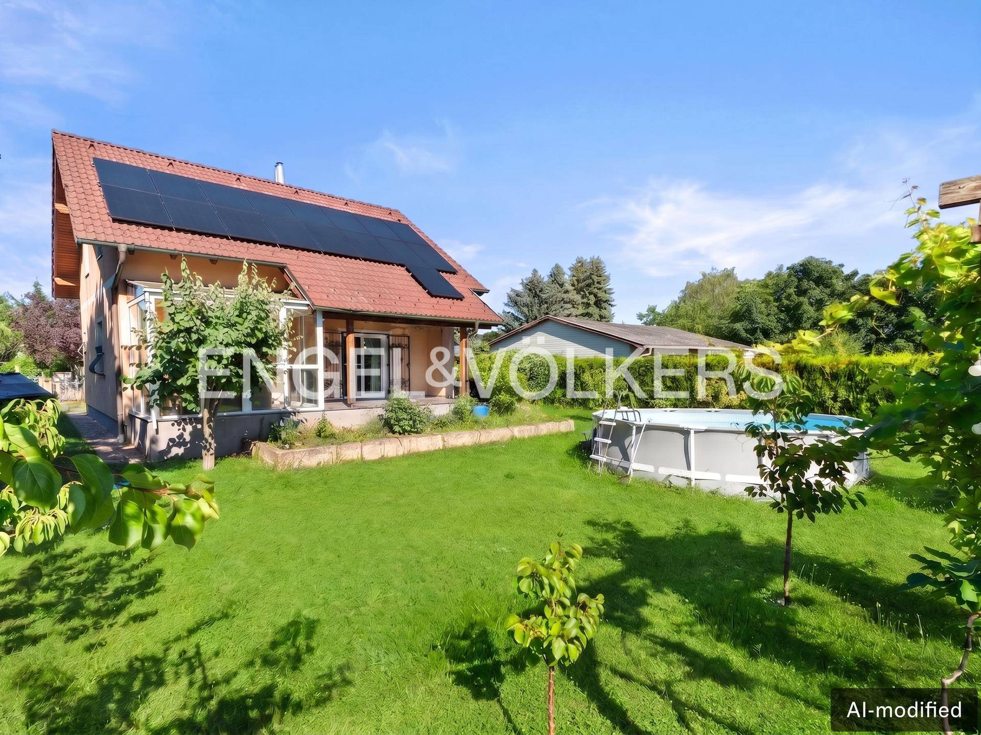 Seitenansicht des Hauses mit weitläufigem Garten und einem Aufstellpool unter blauem Himmel.