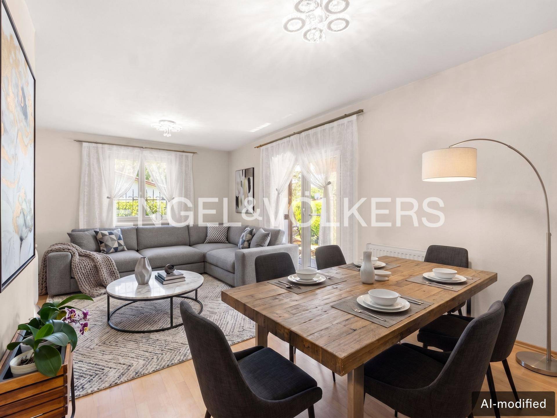 Heller Wohn- und Essbereich mit modernem Sofa, Holztisch und großen Fenstern.