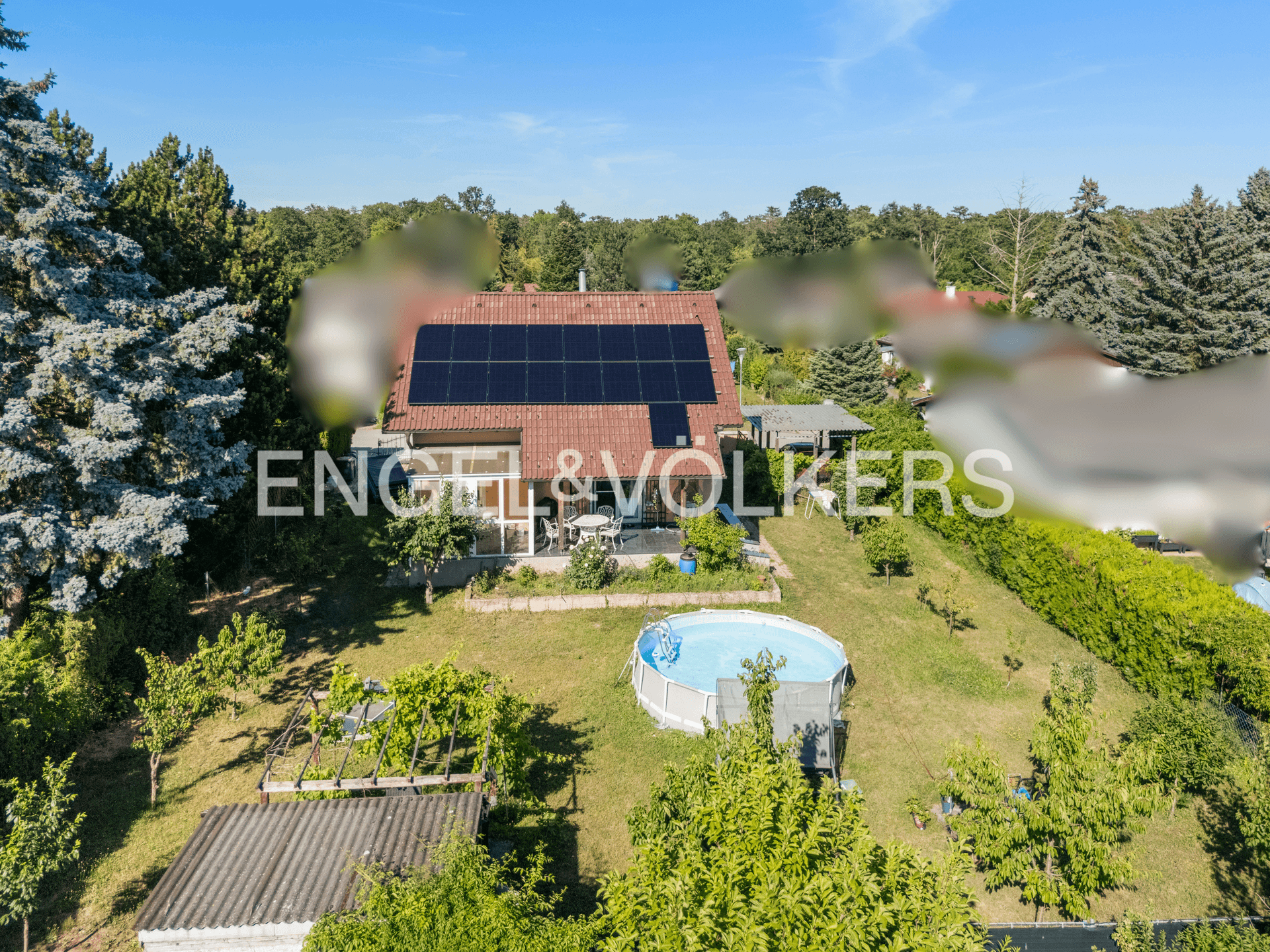 Weitläufiger Garten mit Einfamilienhaus, Aufstellpool und Photovoltaikanlage auf dem Dach.