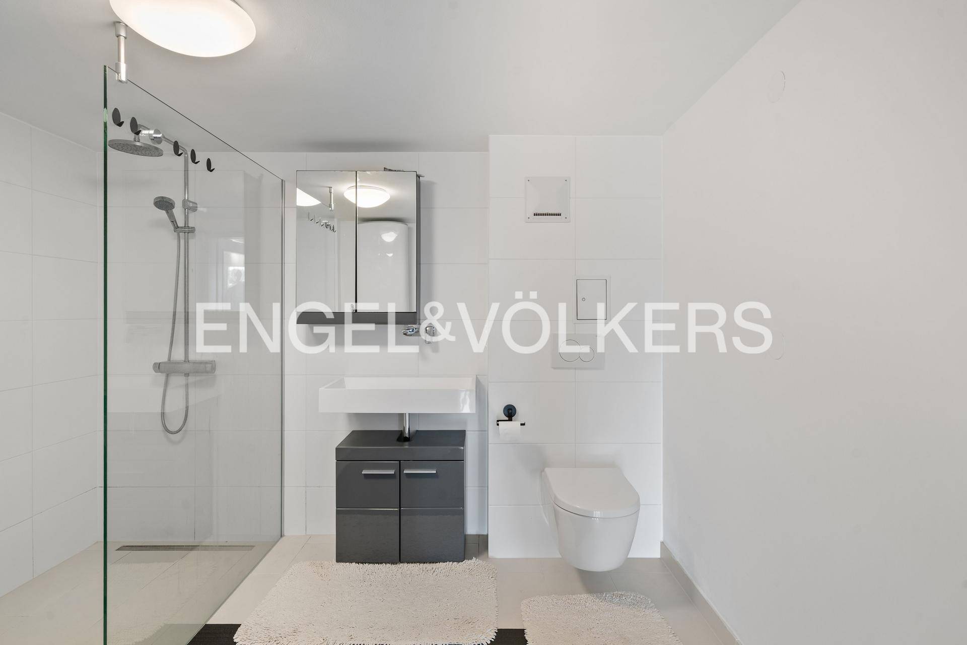 Modernes Badezimmer mit ebenerdiger Dusche, wandhängendem WC und minimalistischem Design.