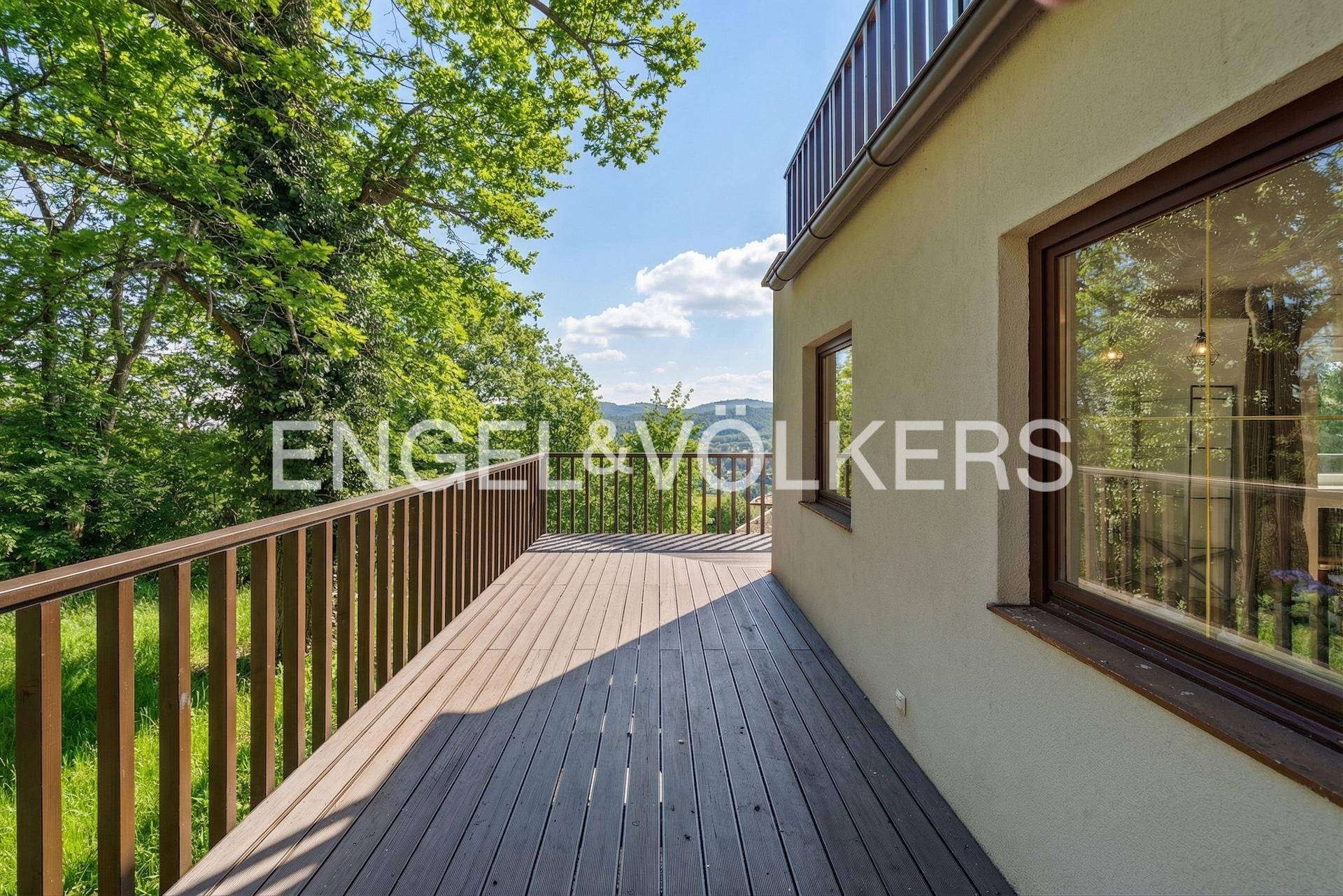 Geräumiger Holzbalkon mit Blick ins Grüne, ideal für entspannte Stunden im Freien.
