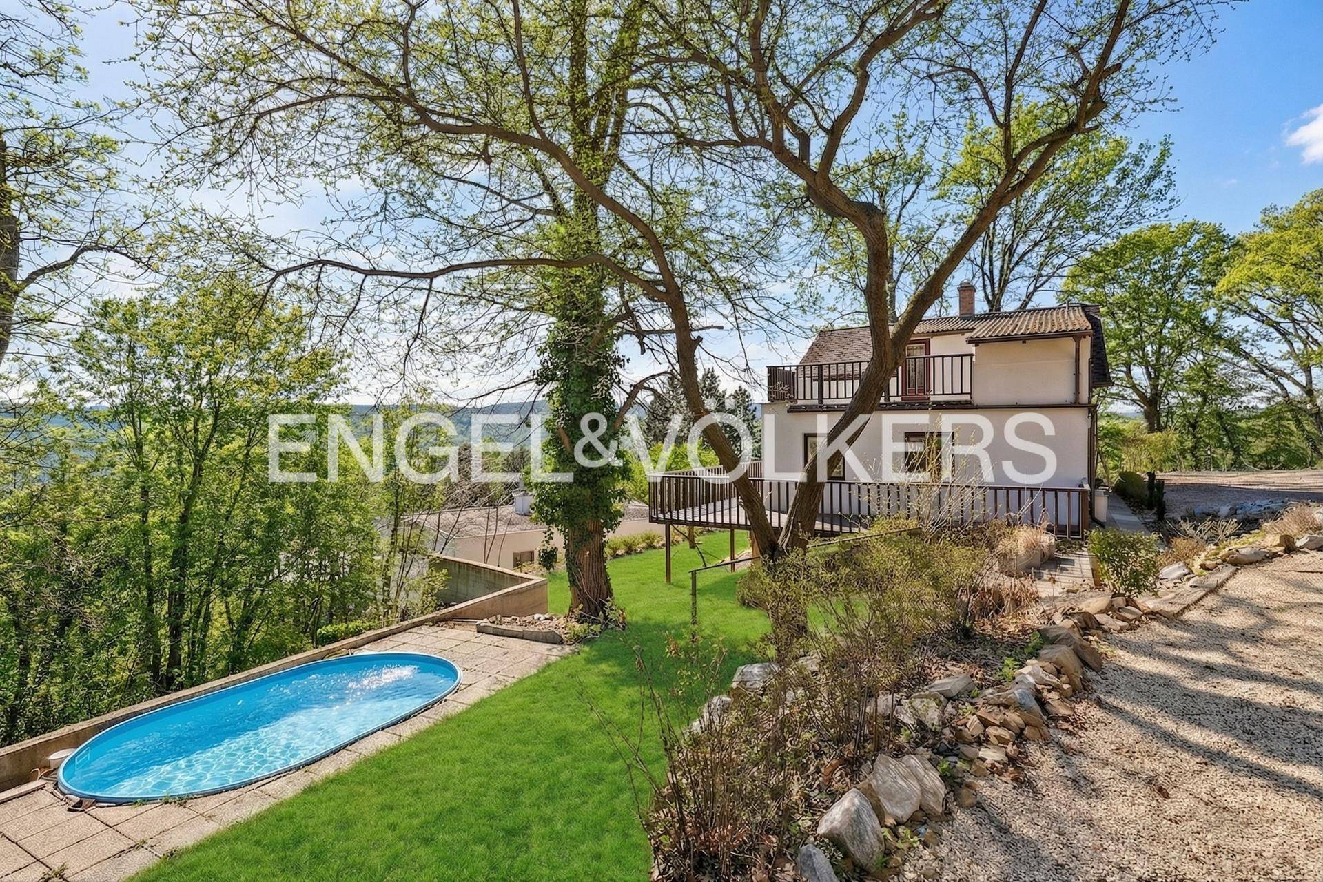 Idyllisches Anwesen mit Außenpool und weitläufigem Garten, umgeben von hohen Bäumen.