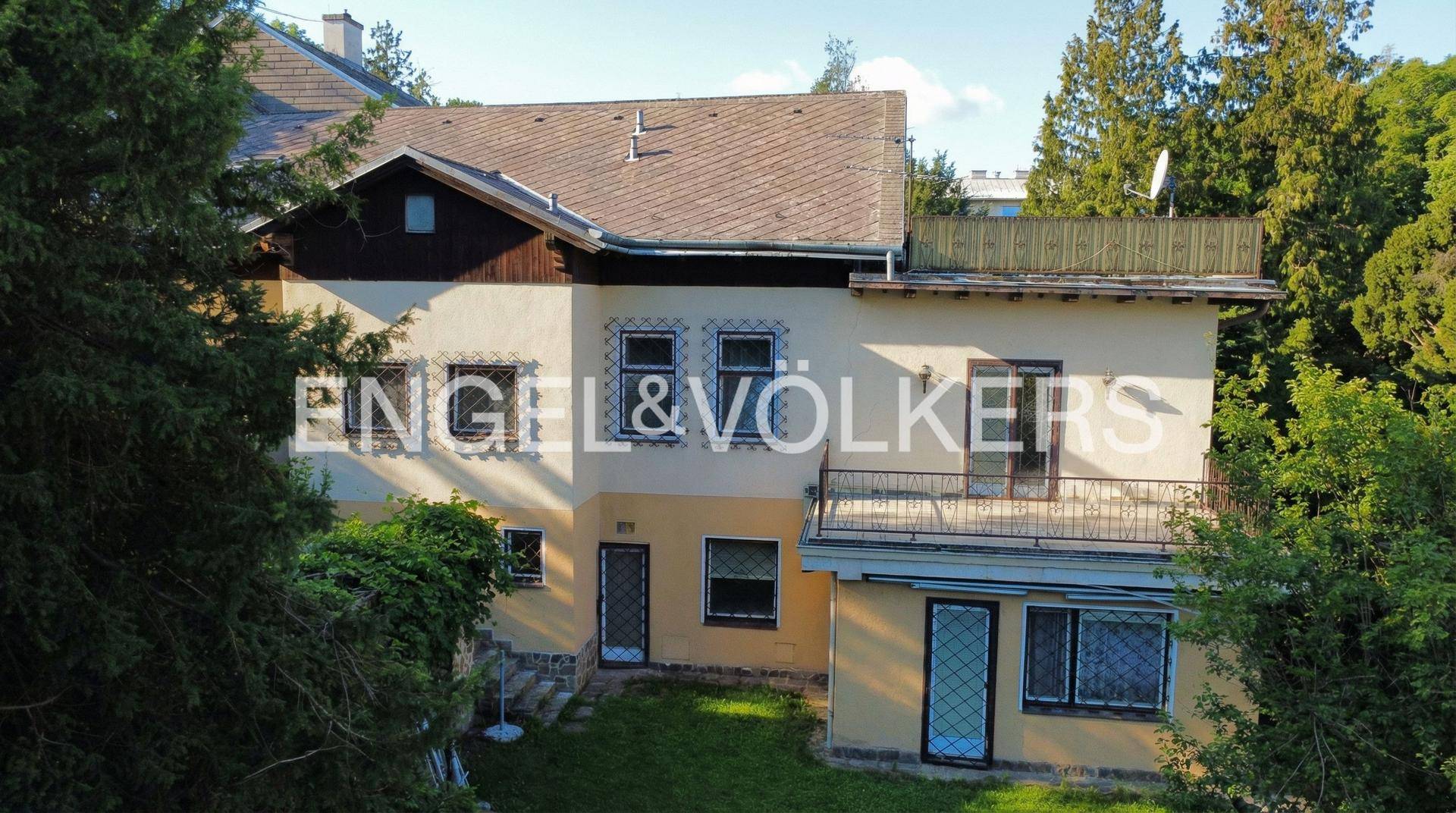 Rückansicht der Villa mit mehreren Fenstern, Balkonen und Zugang zum Gartenbereich.