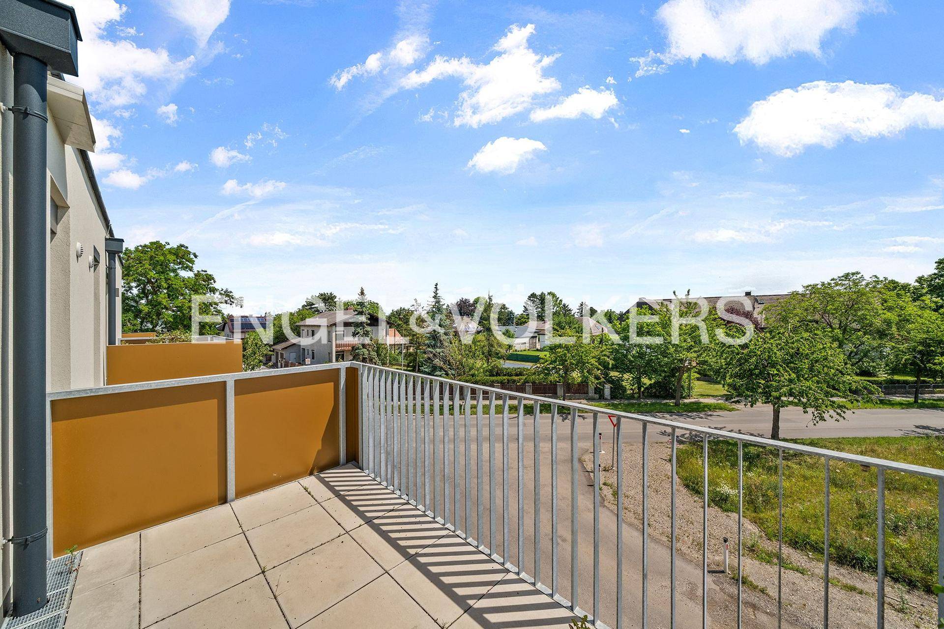Heller Balkon mit Fliesenboden und Blick auf die umliegende grüne Landschaft.