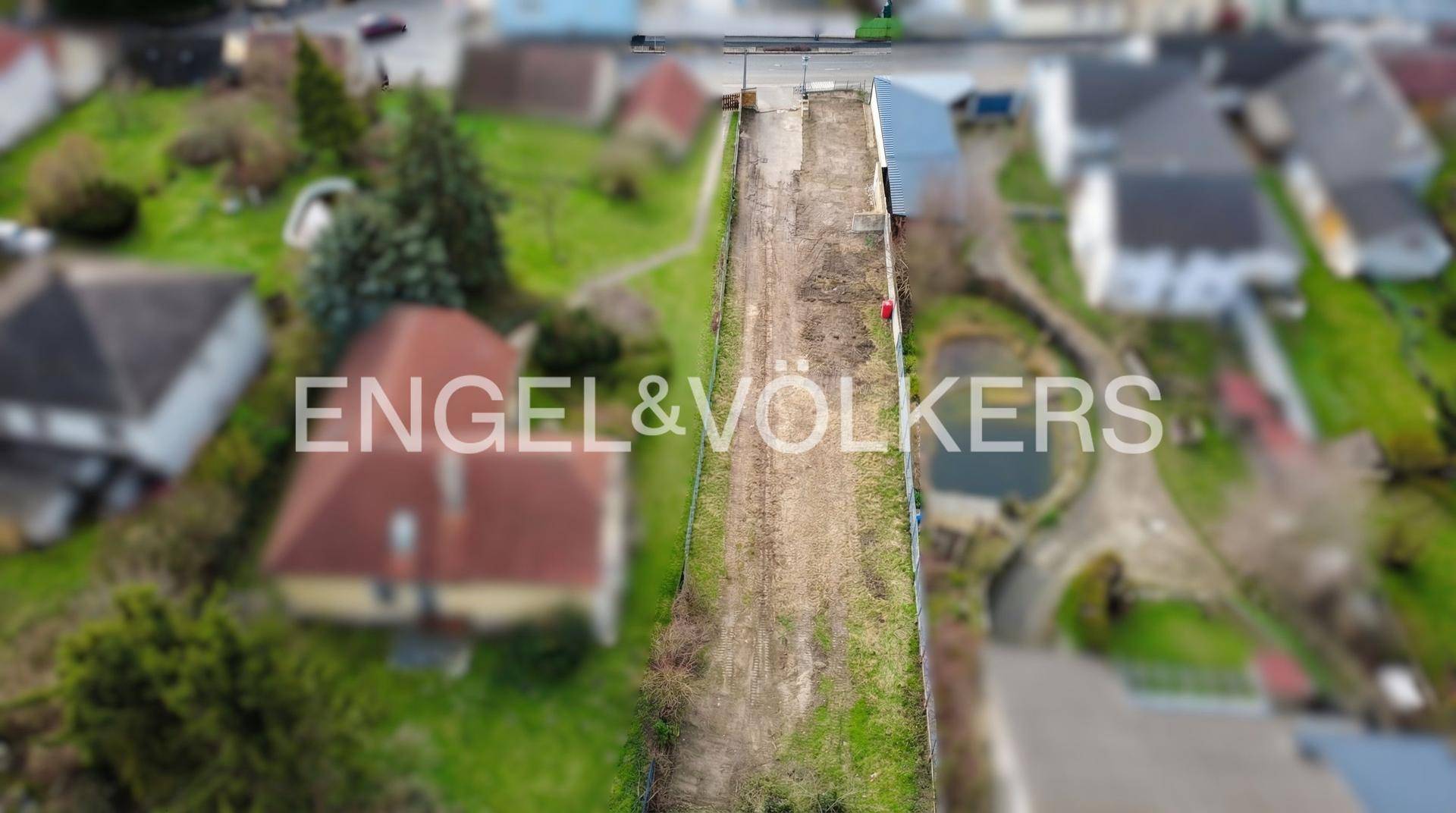 Luftaufnahme eines langgestreckten Grundstücks mit Zufahrtsweg und angrenzenden Gebäuden.