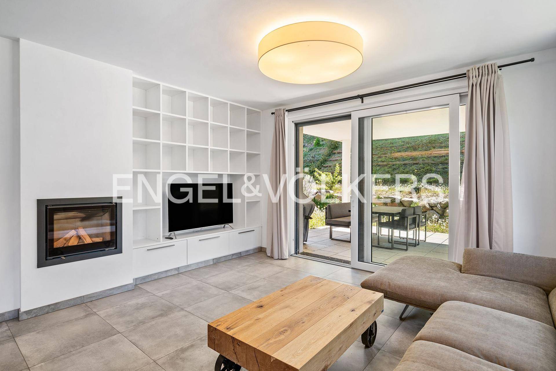 Gemütliches Wohnzimmer mit Kamin, integriertem Regal und direktem Zugang zur Terrasse.