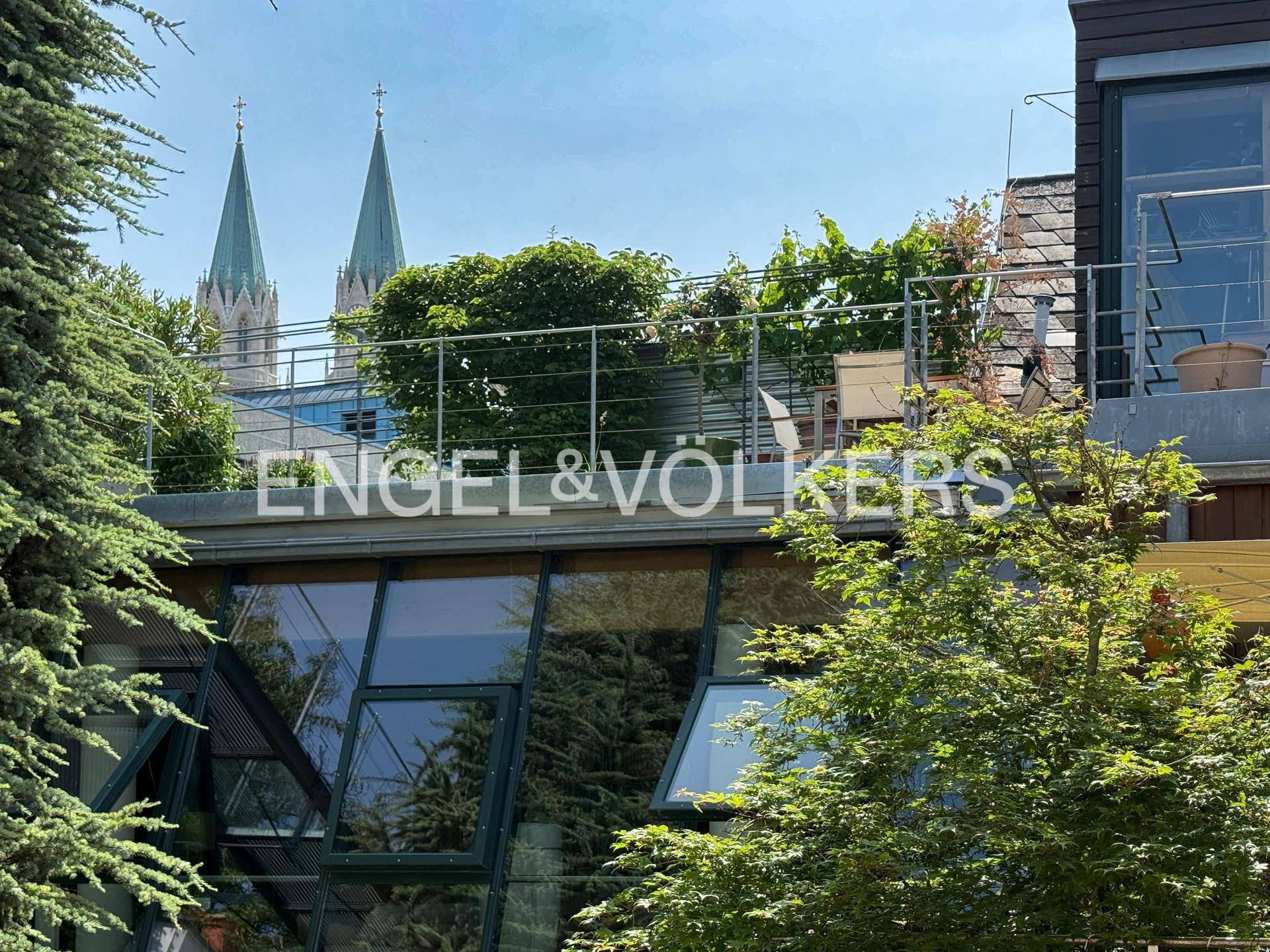 Dachterrasse mit Sitzgelegenheiten und Blick auf die Kirchtürme der Stadt.