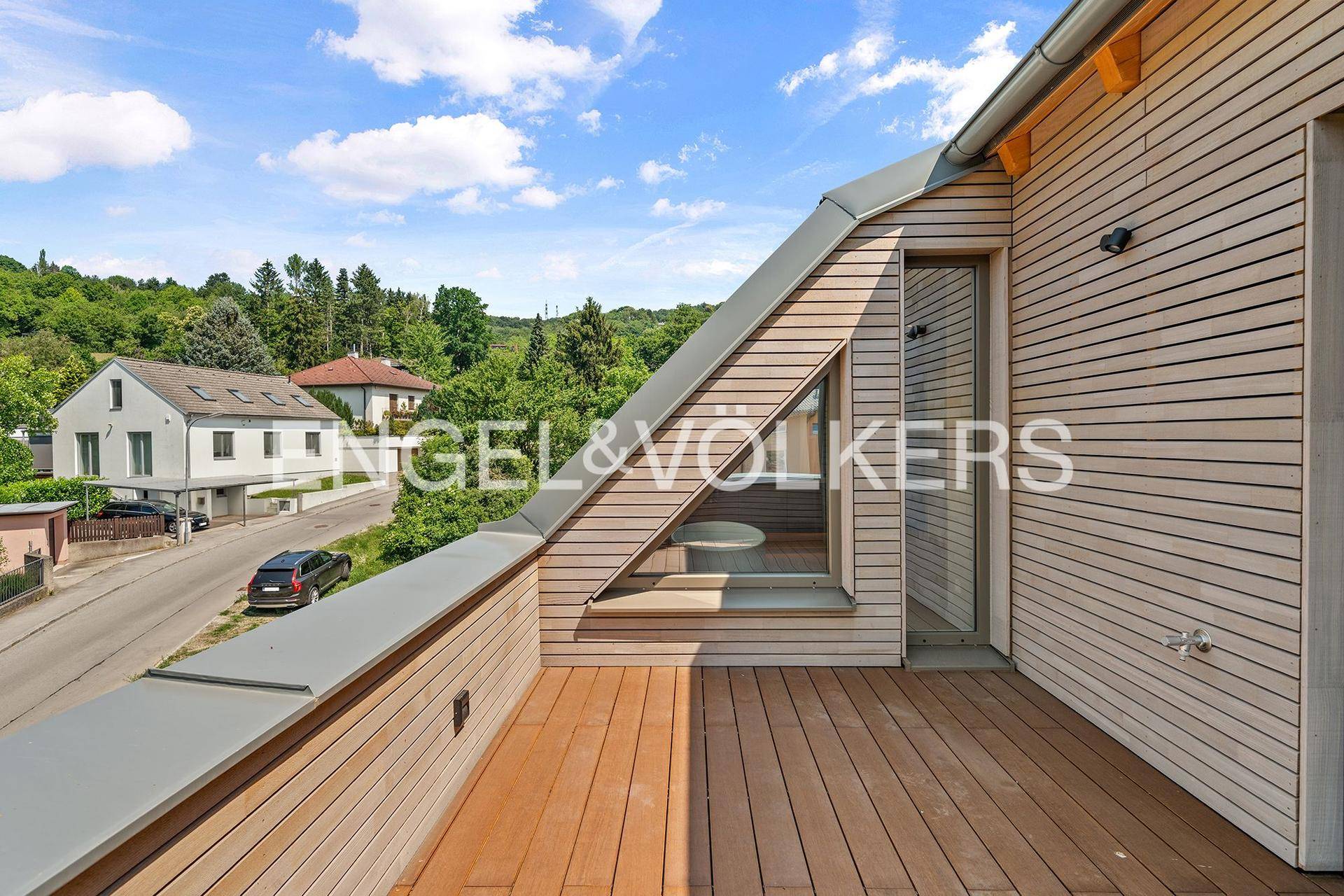 Geräumige Dachterrasse mit Holzboden und Blick auf die grüne Umgebung.