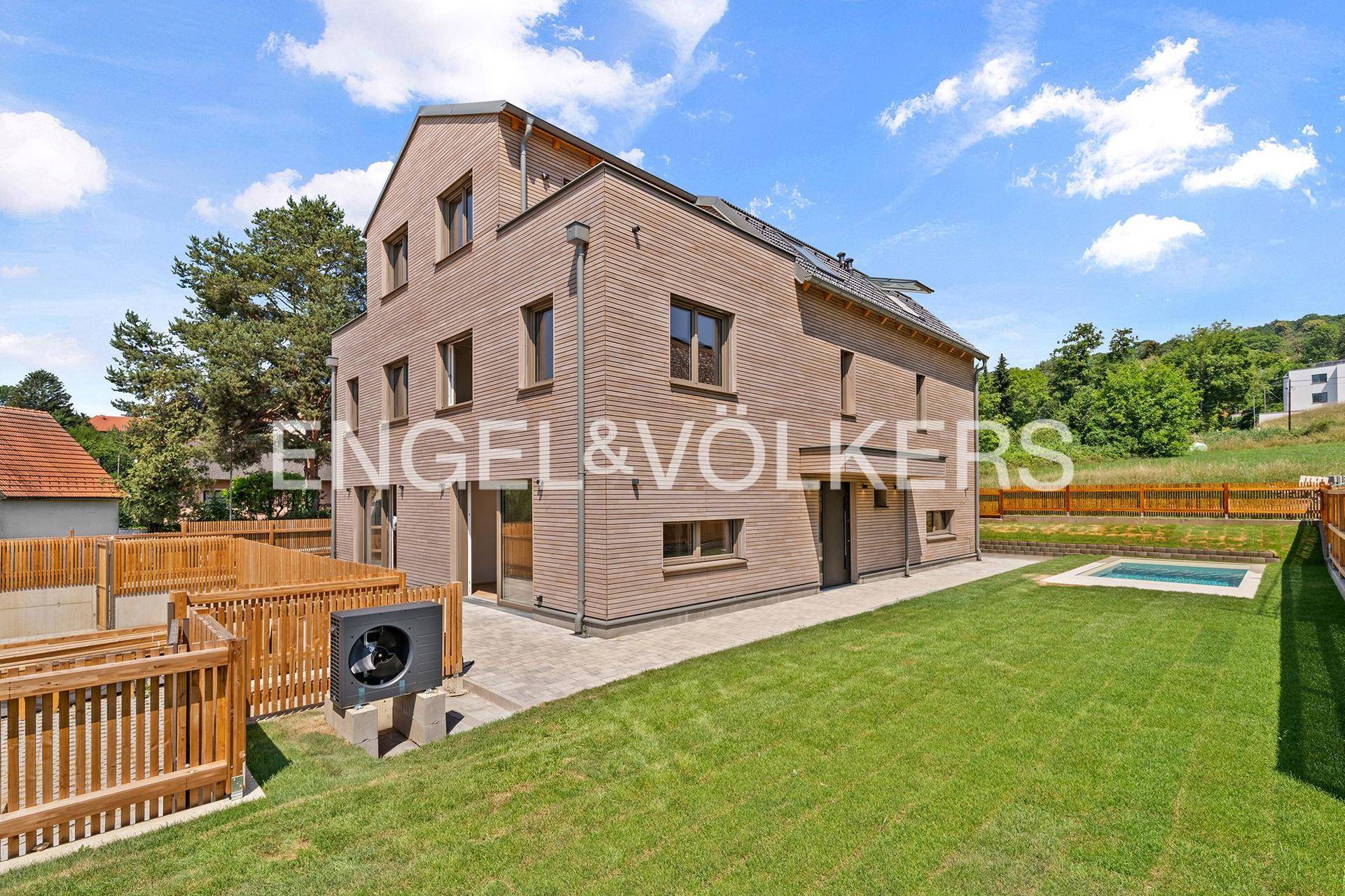 Rückansicht des modernen Hauses mit Holzfassade, Garten, Pool und Wärmepumpe.