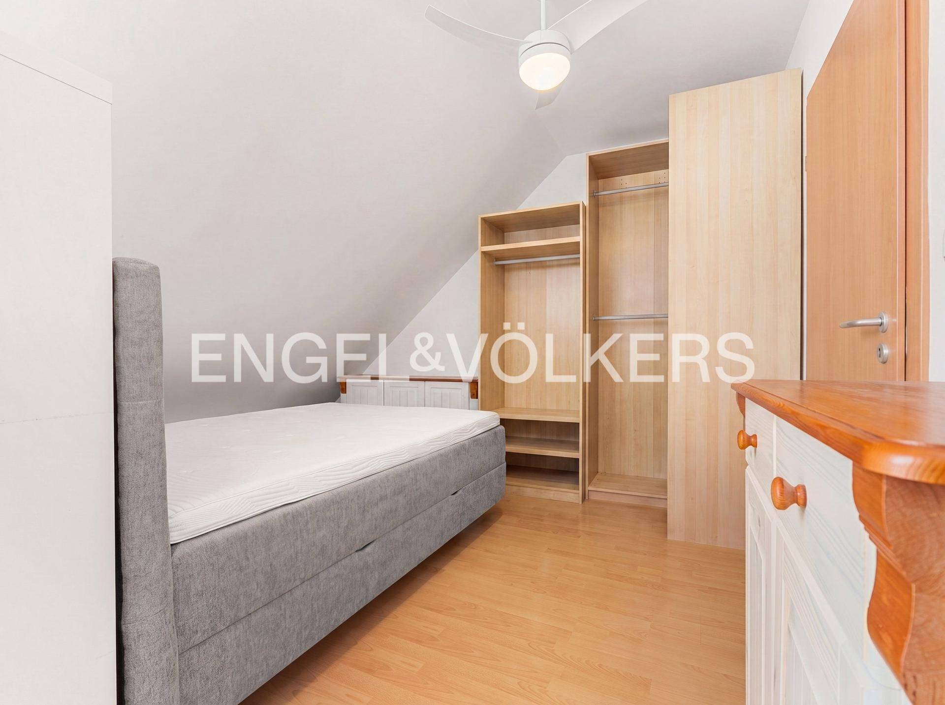 Schlafzimmer im Dachgeschoss mit Einzelbett, offenem Kleiderschrank und schrägen Wänden.