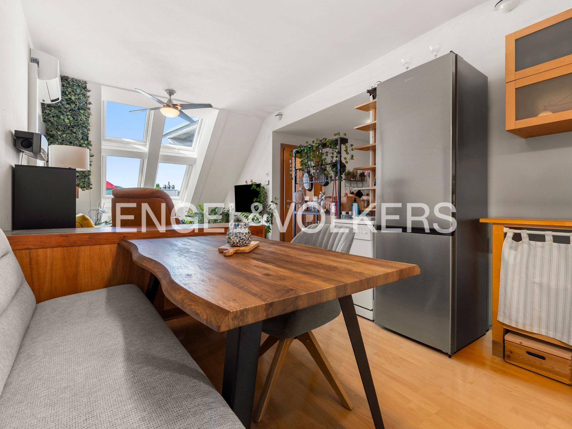 Heller Essbereich mit Holztisch, Sitzbank und Blick in den offenen Wohnbereich mit Dachfenstern.