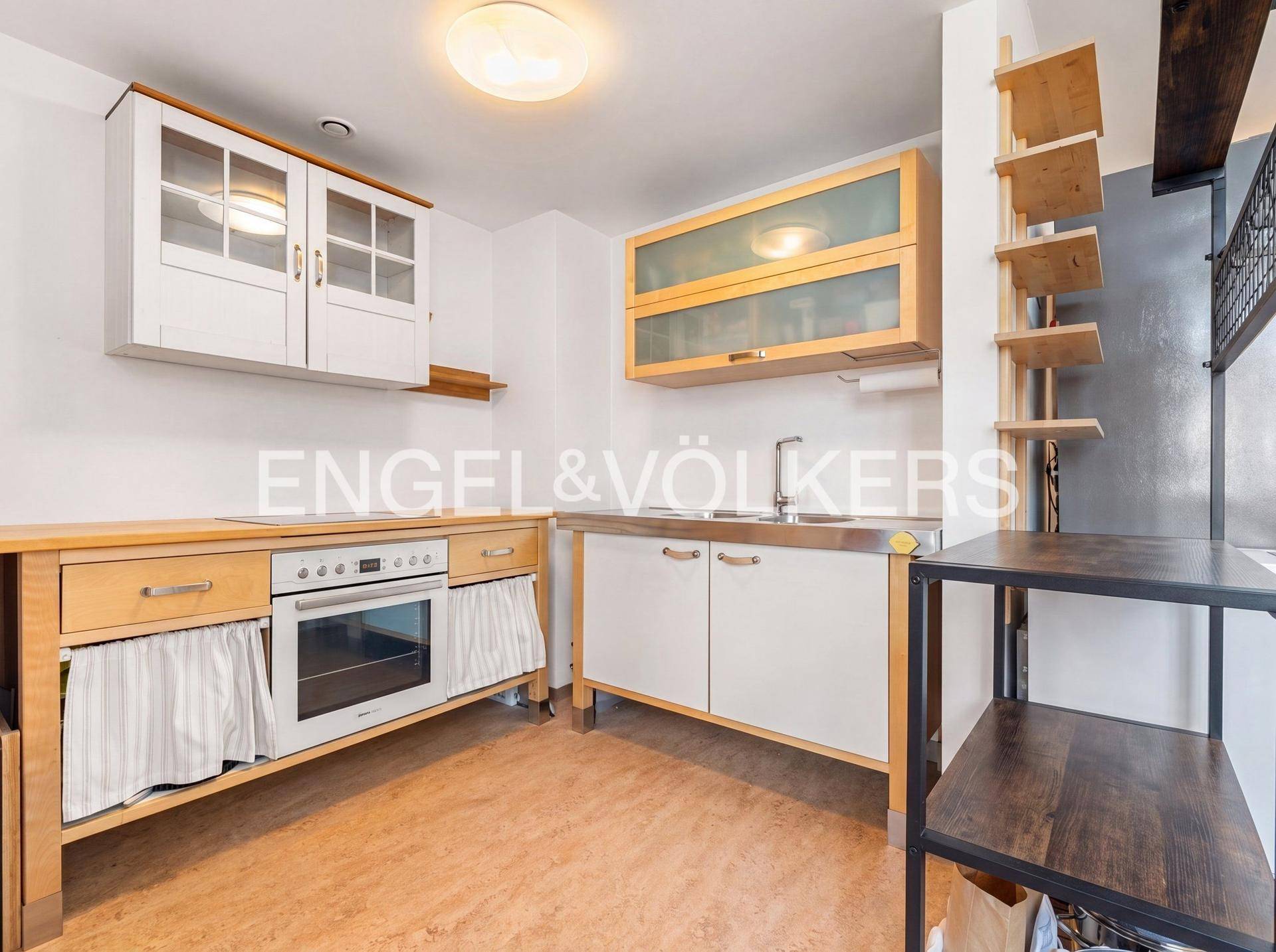 Funktionale Küche mit Holzschränken, Backofen und Spüle, ausgestattet für den täglichen Gebrauch.