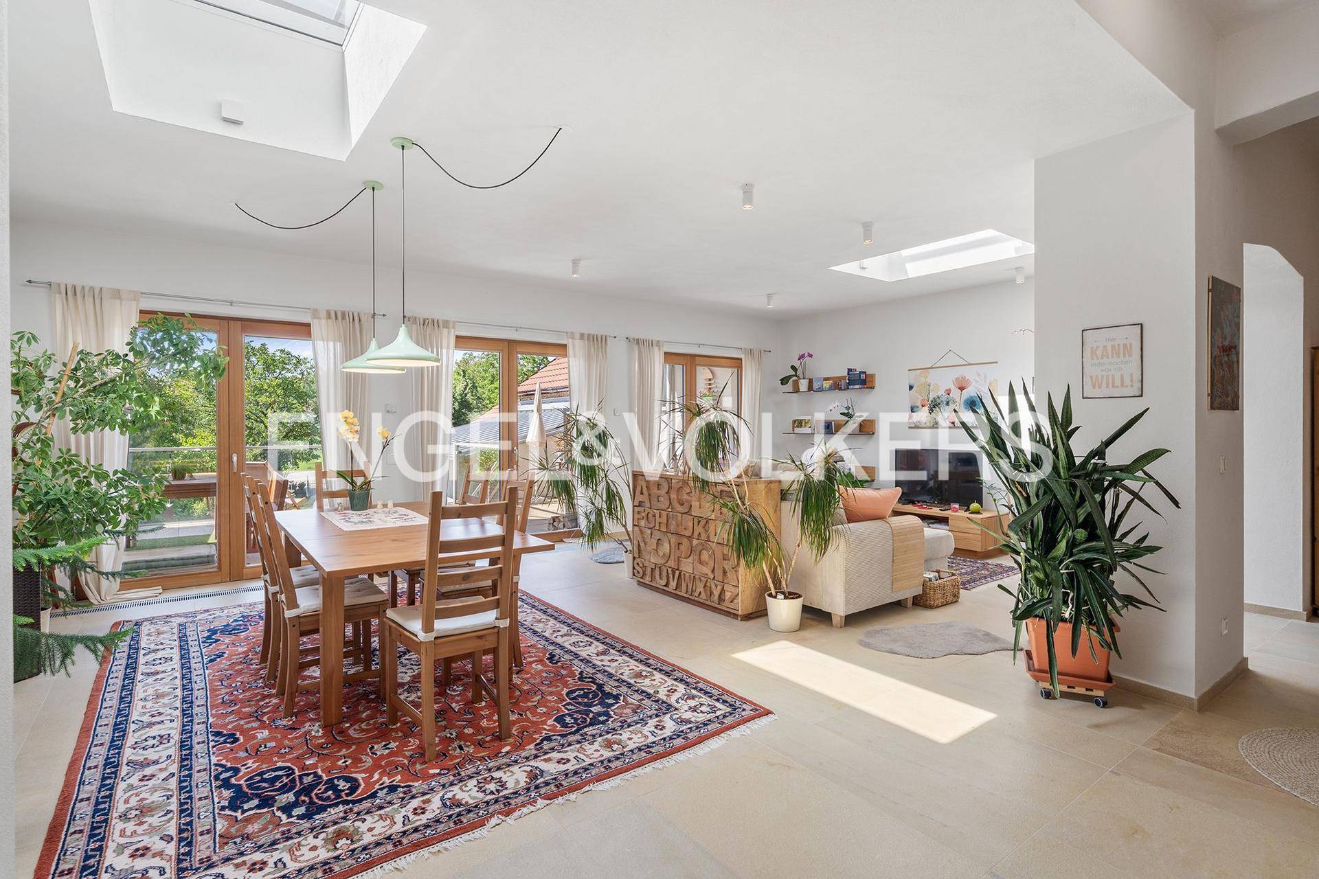 Offener Wohn- und Essbereich mit viel Tageslicht, Pflanzen und Zugang zur Terrasse.