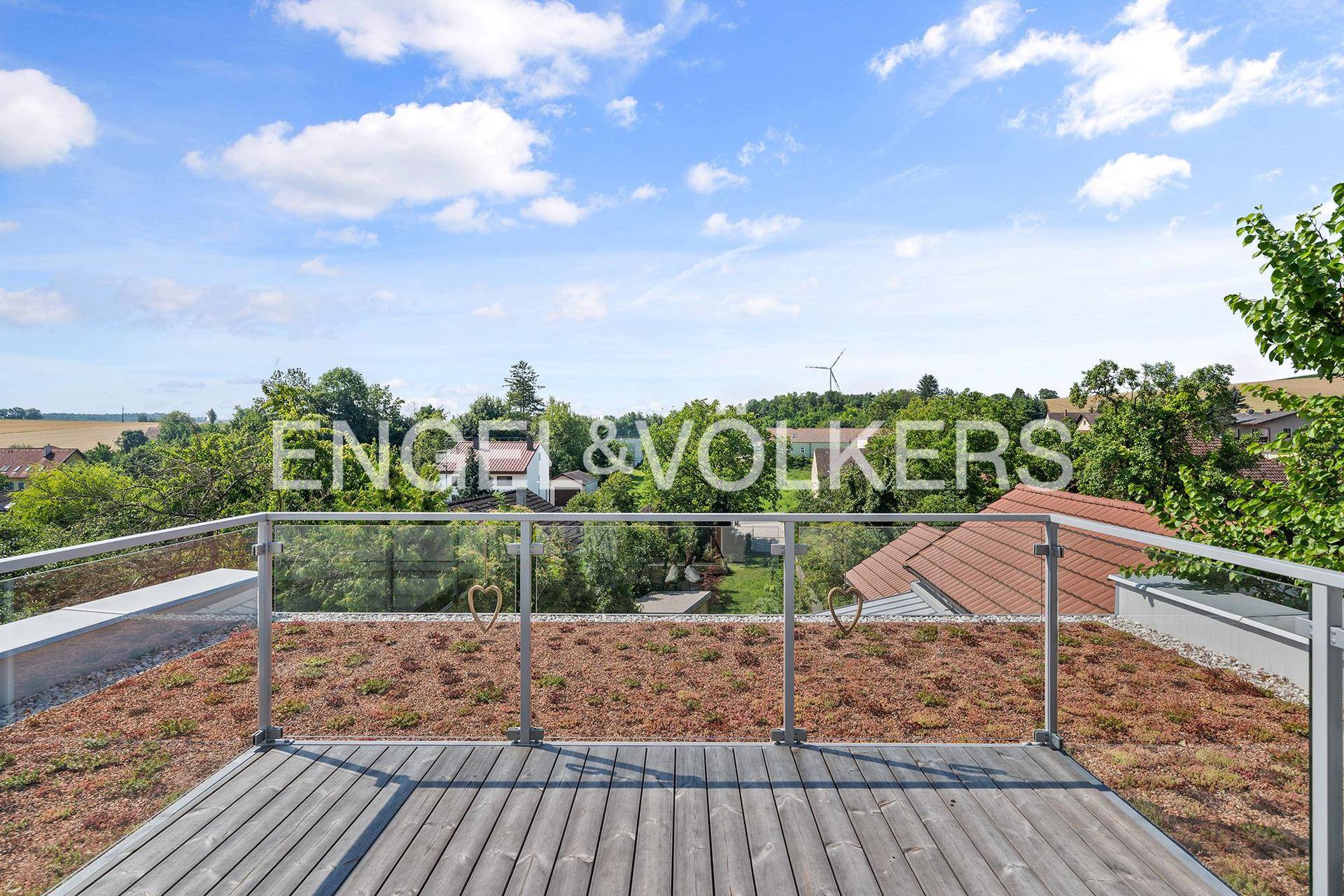 Dachterrasse mit Holzboden und weitem Blick über die Landschaft und Windräder.