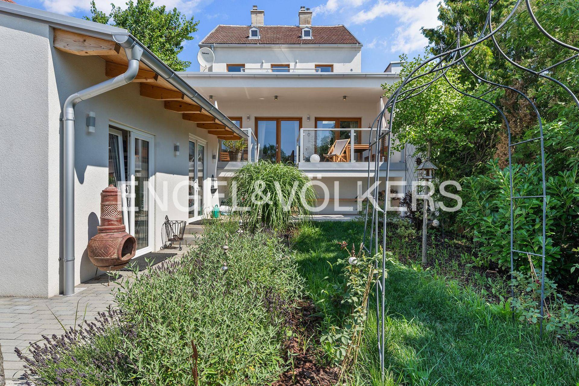 Gepflegter Gartenbereich mit Terrasse, Pflanzen und Blick auf das Hauptgebäude.