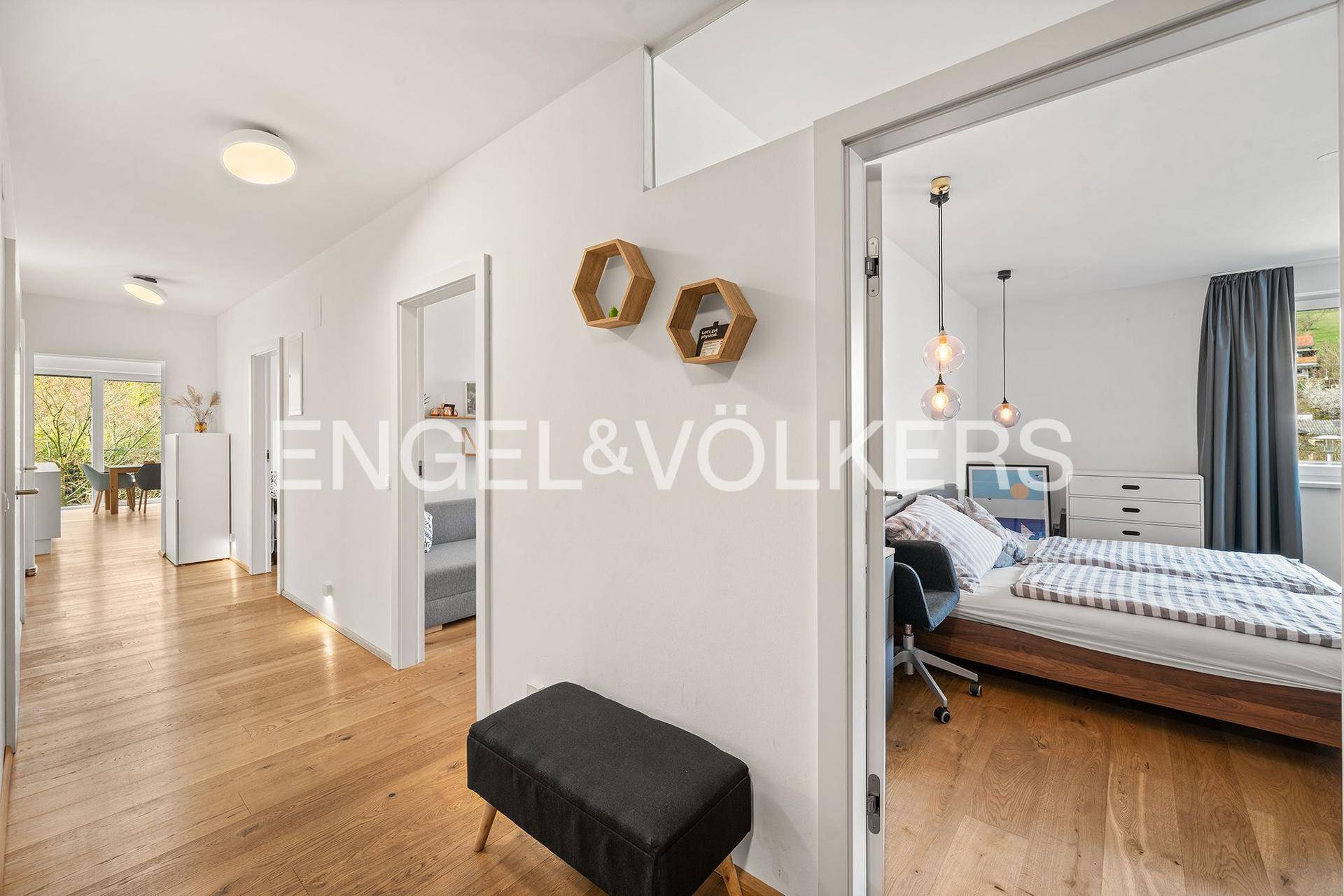 Heller Flur mit Holzboden und Zugang zu verschiedenen Zimmern, inklusive Schlafzimmer.