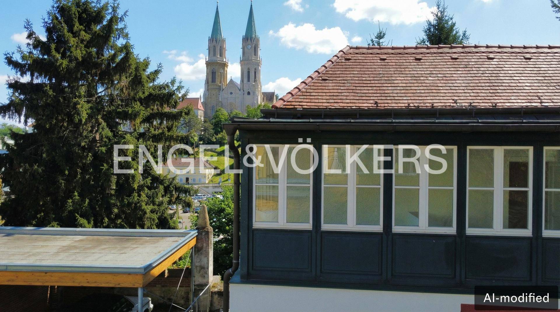 Detailansicht des Gebäudes mit traditionellem Dach und Kirchtürmen im Hintergrund.