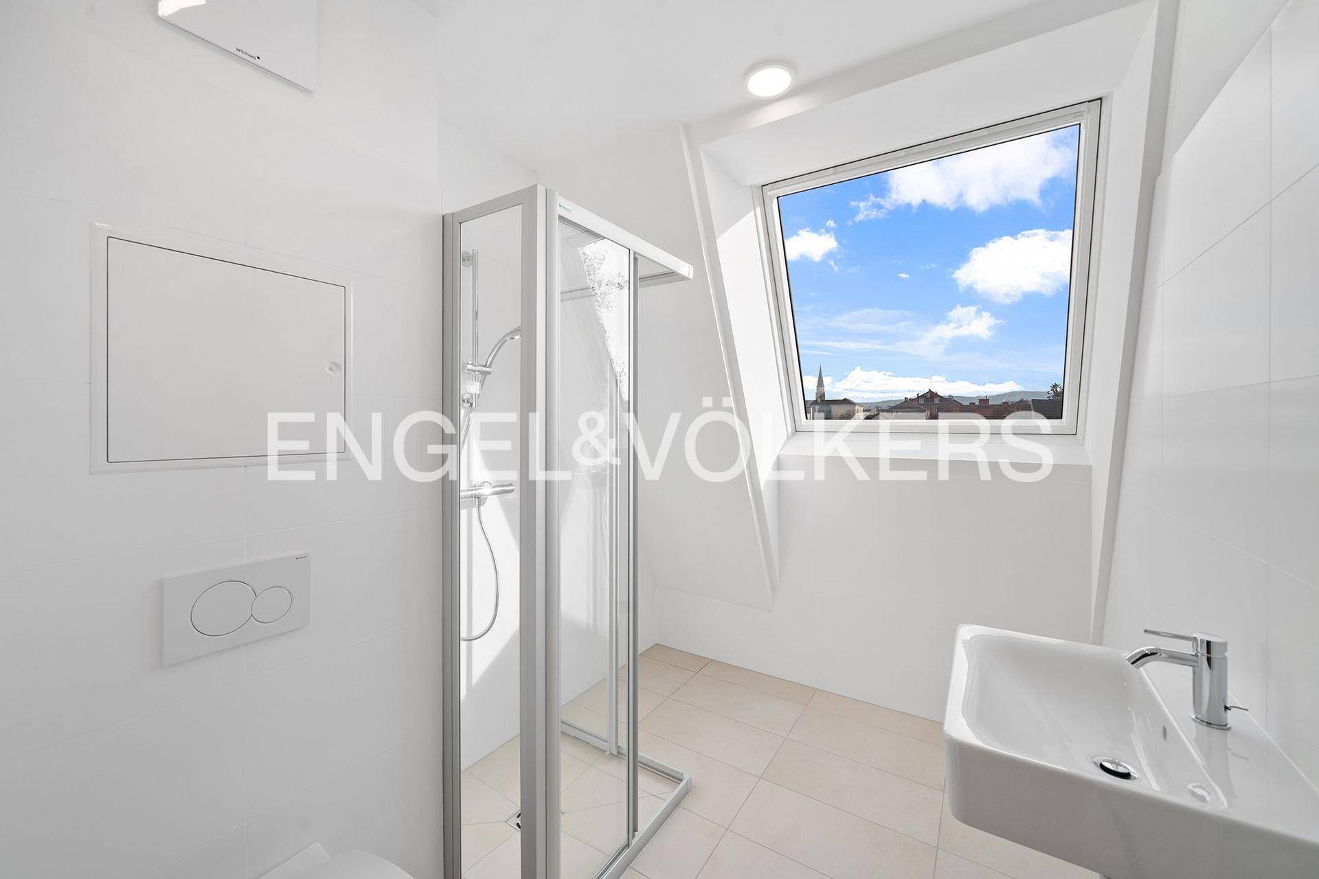 Helles Badezimmer mit Dusche, Waschbecken und Dachfenster.