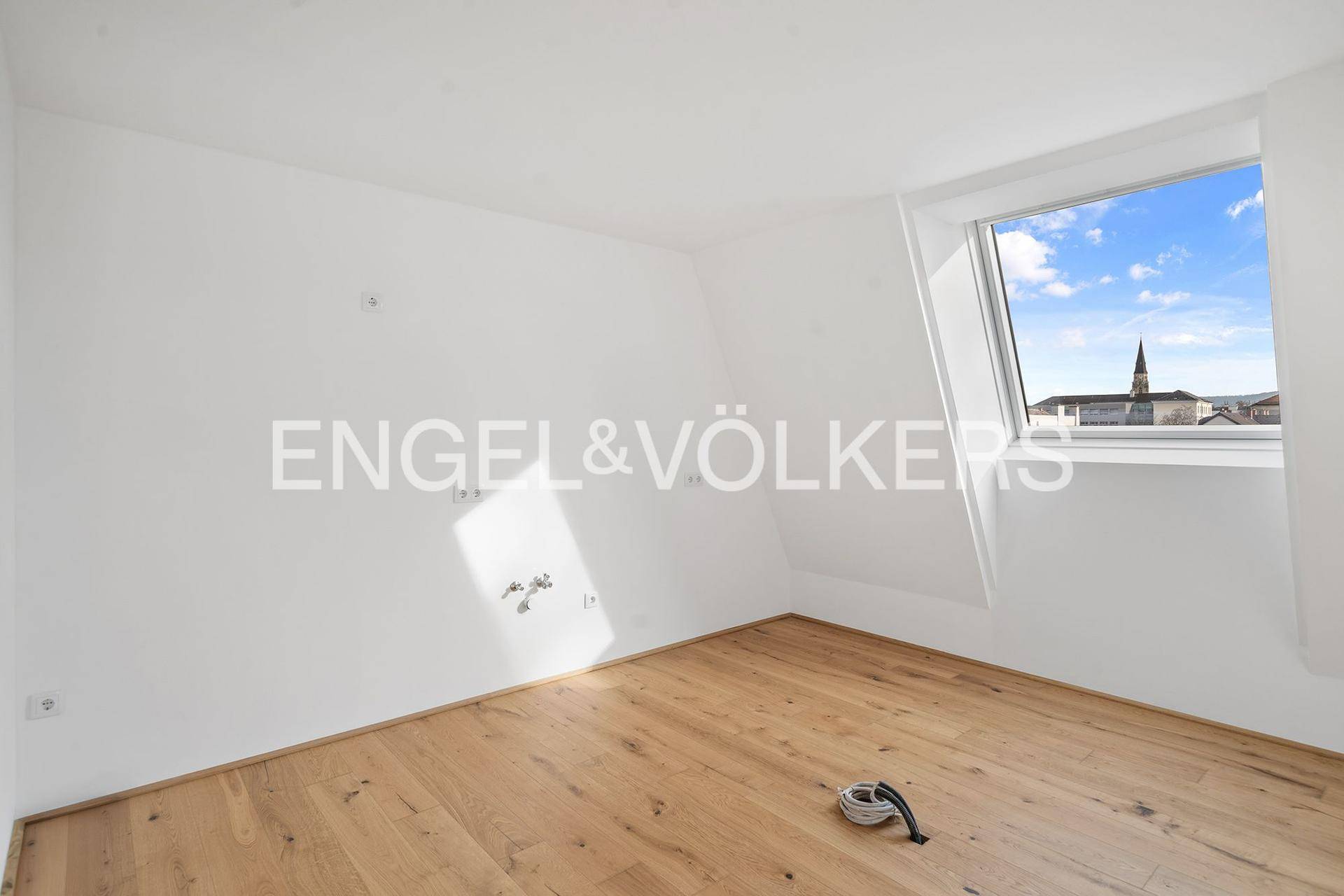 Leeres Zimmer mit Holzboden und Dachfenster, ideal als Schlaf- oder Arbeitszimmer.