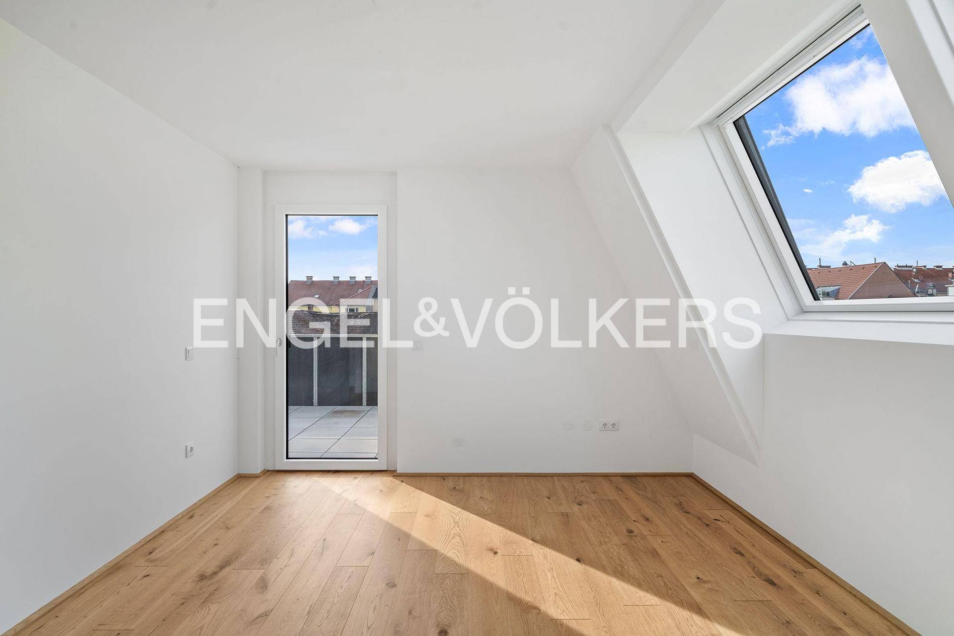 Helles, leeres Schlafzimmer mit Holzboden, Dachfenster und Terrassenzugang.