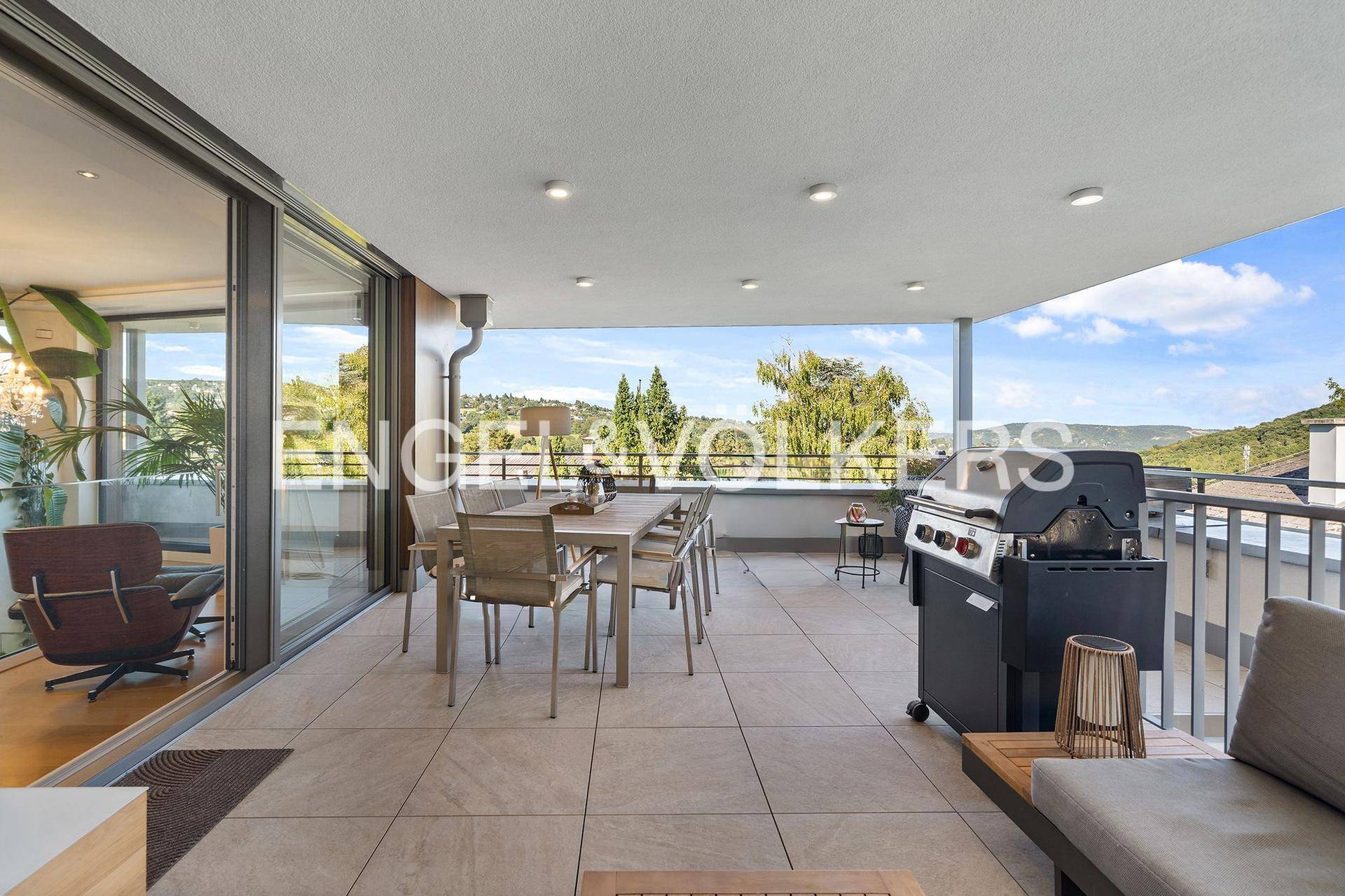 Geräumige Terrasse mit Esstisch, Grillbereich und Panoramablick ins Grüne.