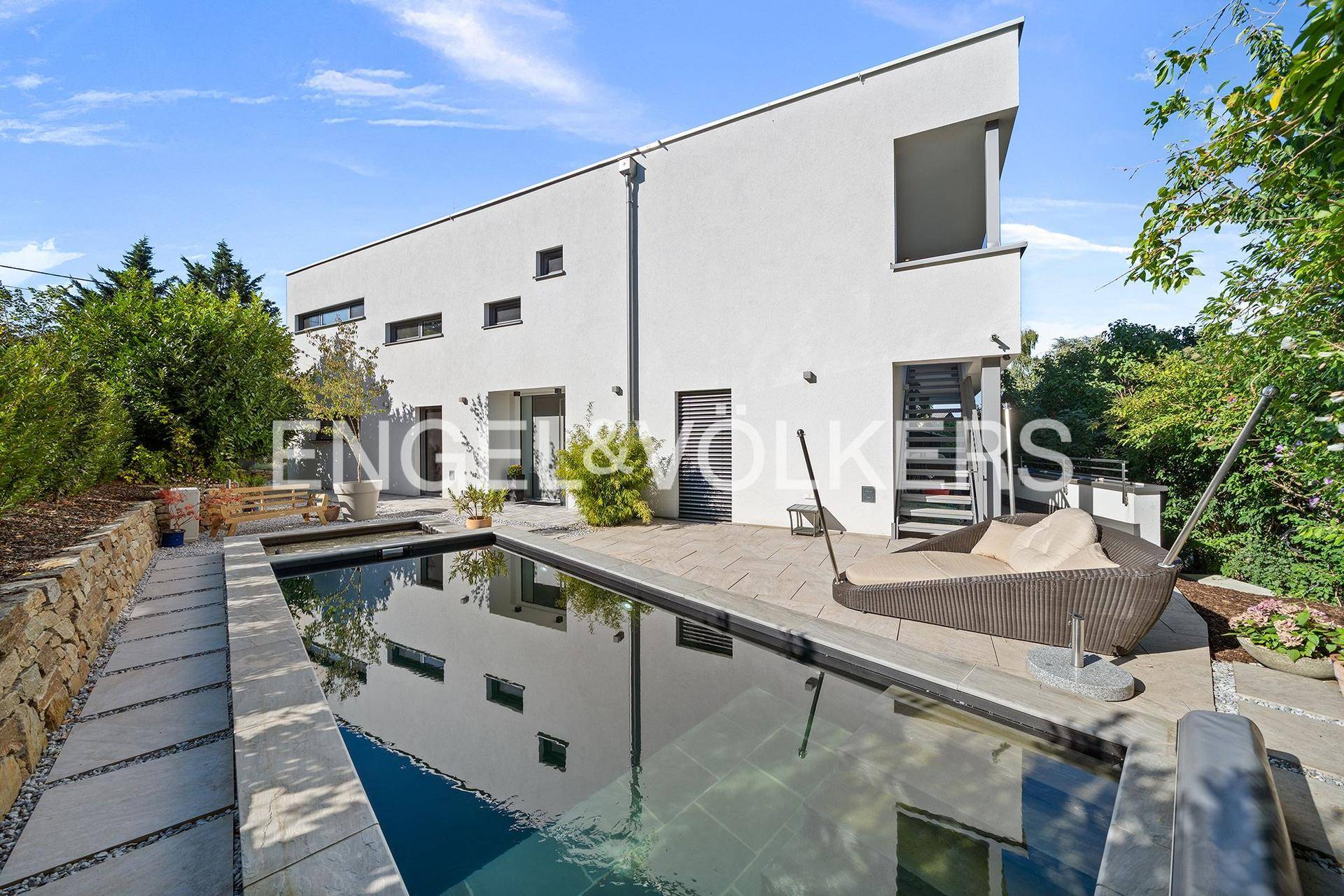 Außenbereich mit modernem Pool, Liegefläche und der weißen Fassade des Hauses.