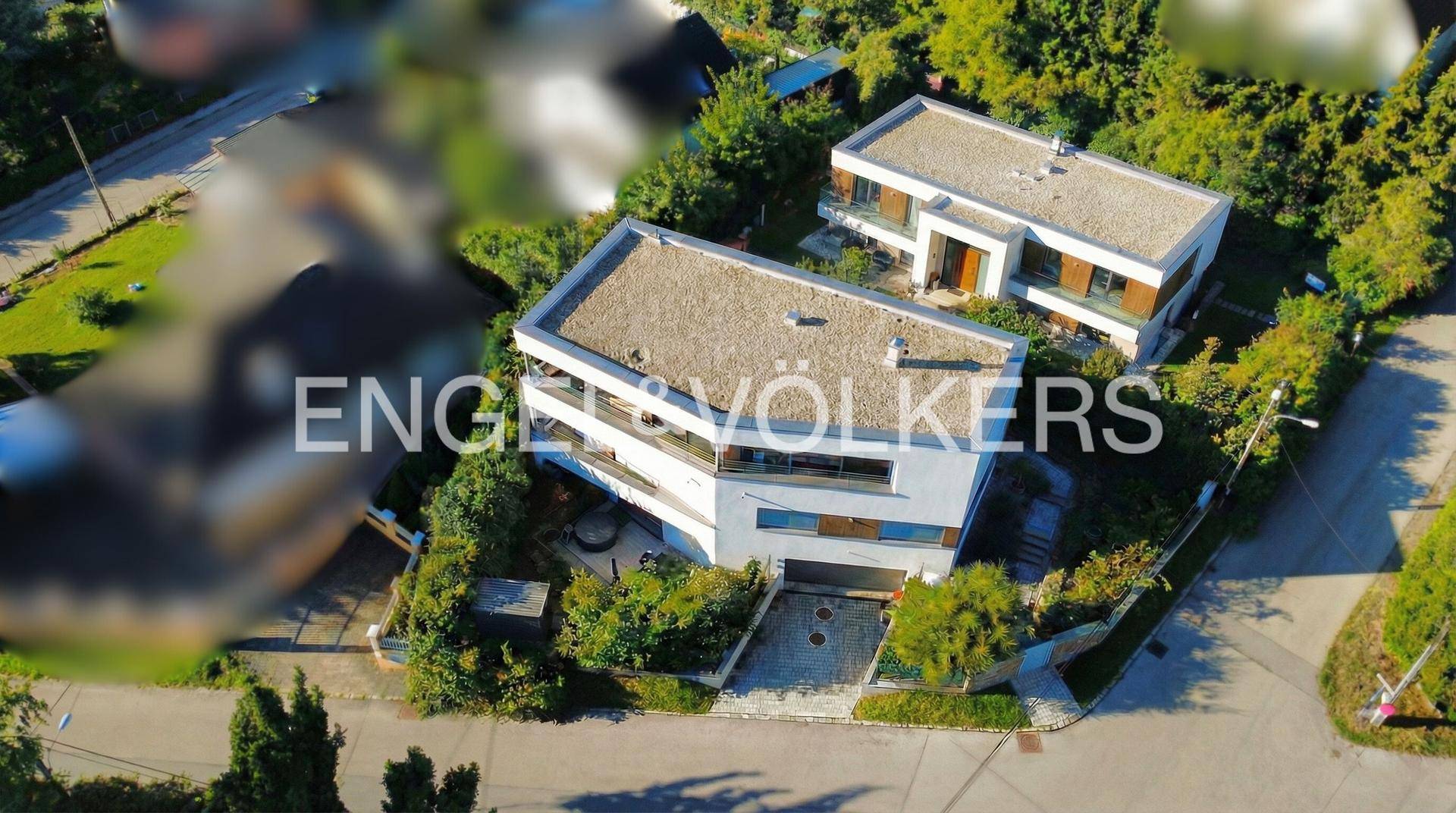 Luftaufnahme von zwei modernen Häusern mit Flachdächern in grüner Umgebung.