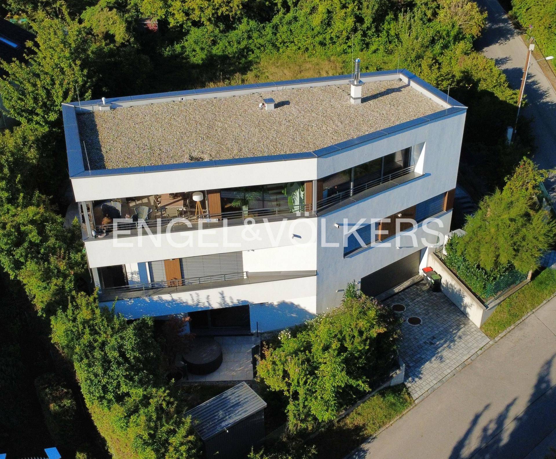 Moderne Architektur des Hauses von oben, umgeben von viel Grün und Bäumen.