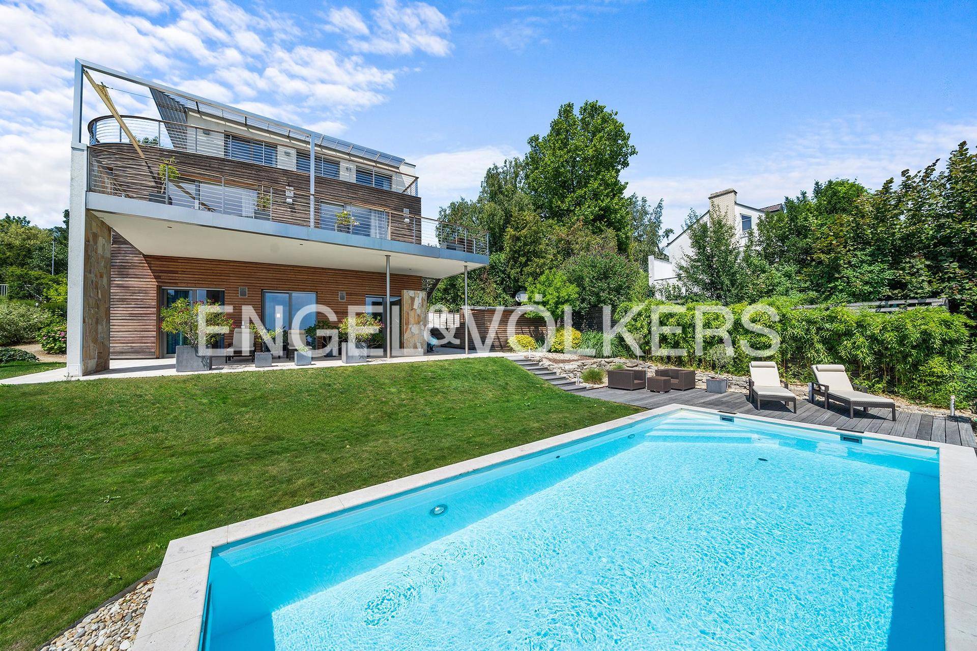 Ansicht der modernen Villa vom Garten aus mit Swimmingpool und Holzterrasse.