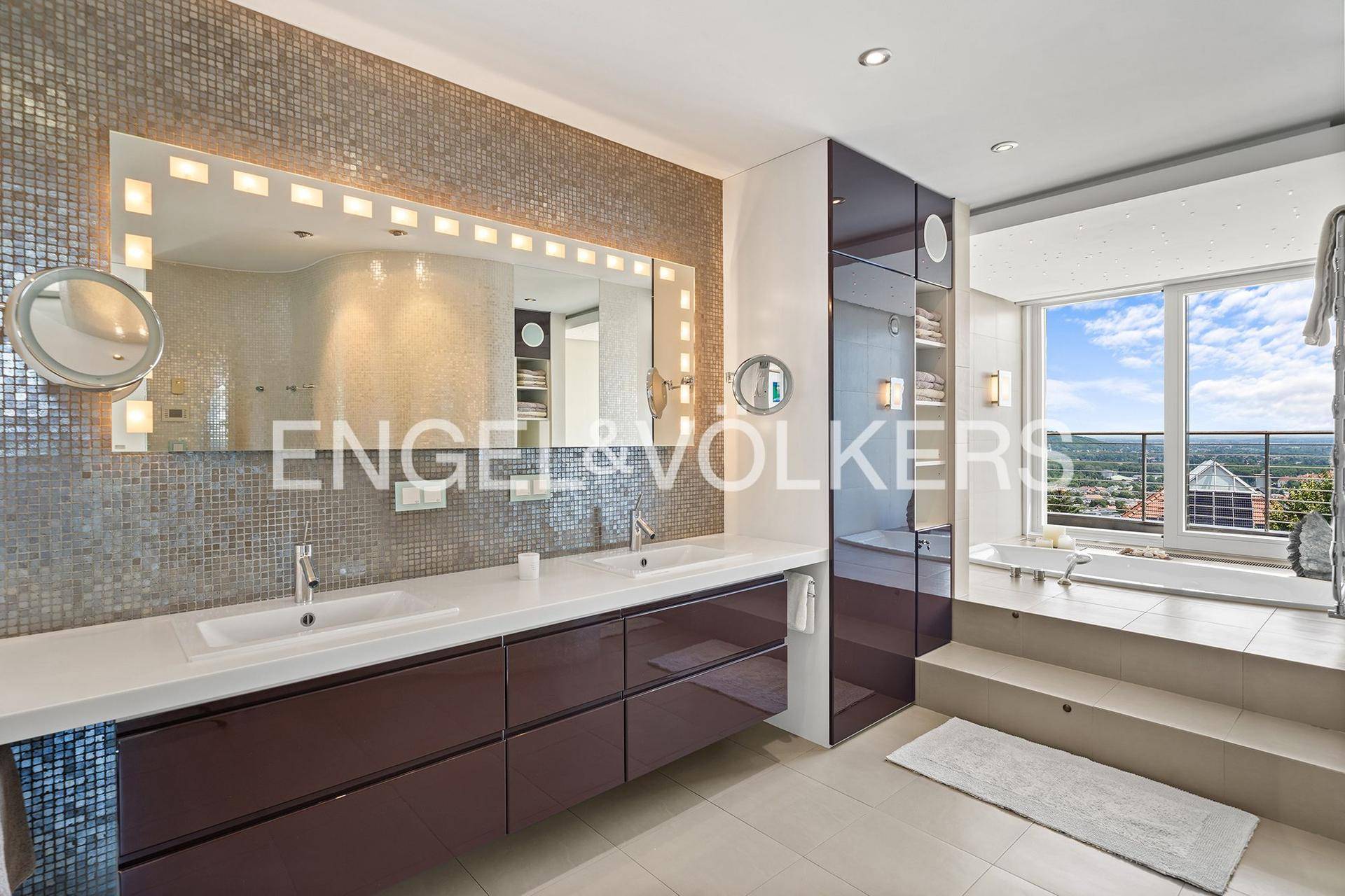 Luxuriöses Badezimmer mit Doppelwaschbecken, Mosaikfliesen und erhöhter Badewanne mit Aussicht.