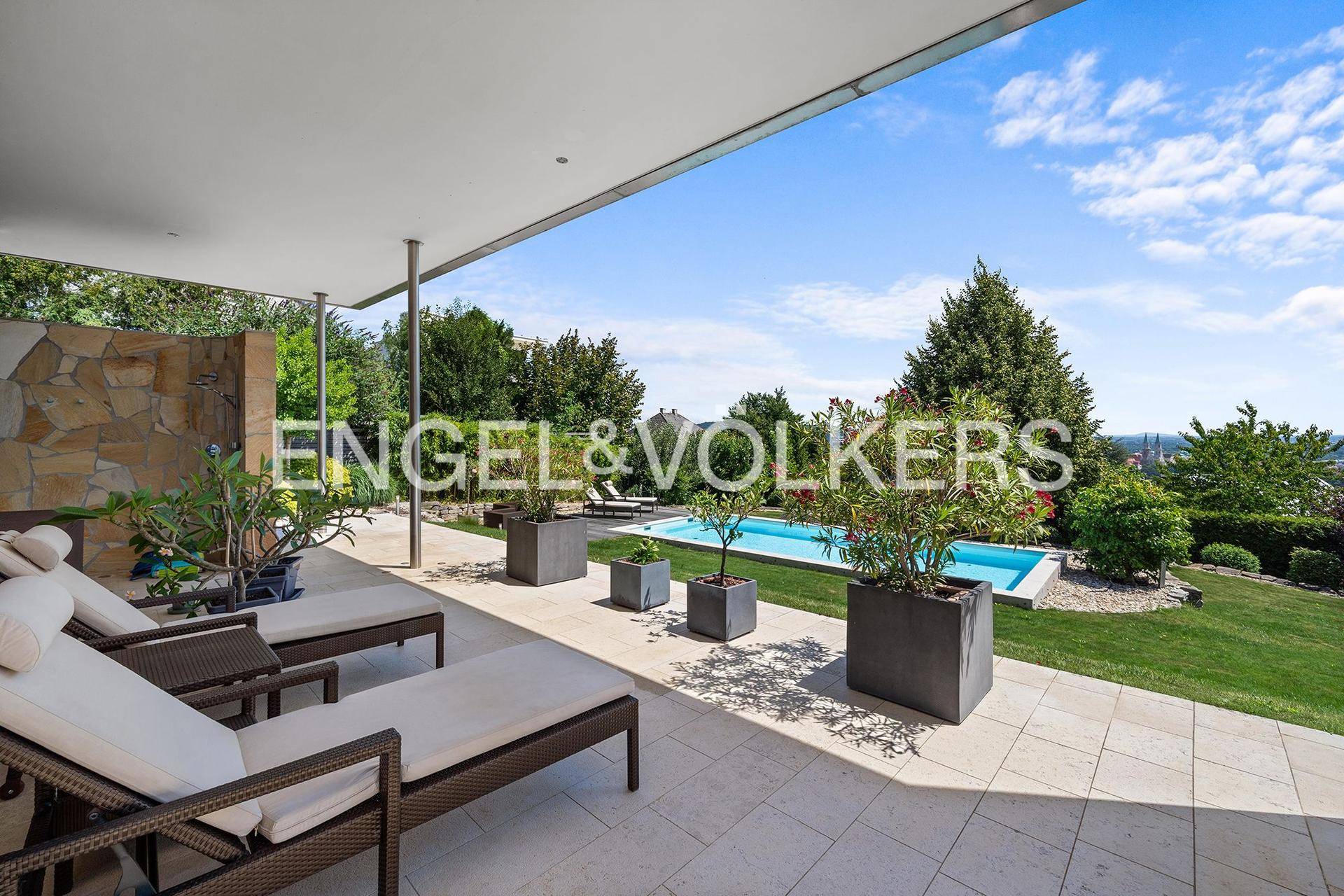 Überdachte Terrasse mit bequemen Liegestühlen und Blick auf den Pool und die Landschaft.