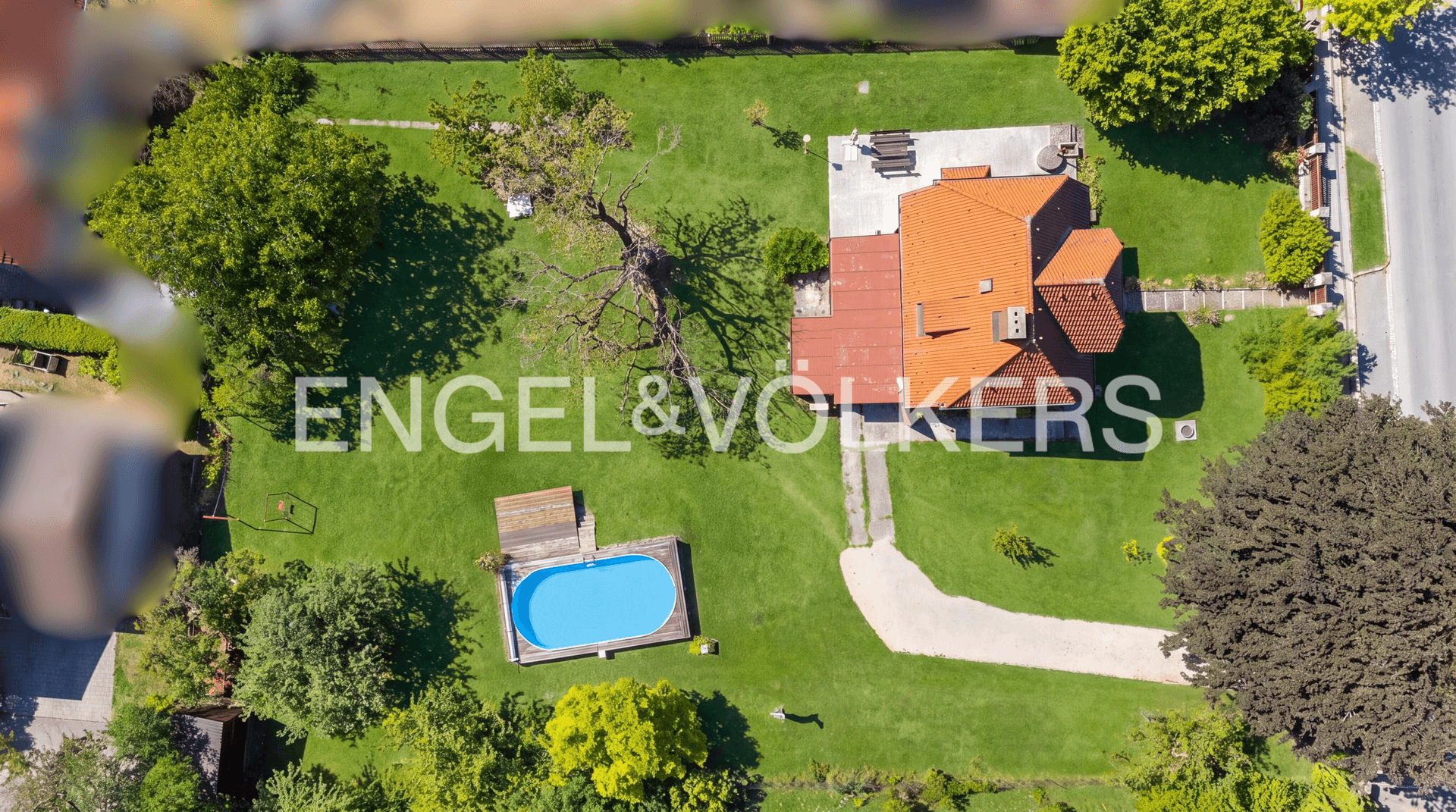 Vogelperspektive des Anwesens mit Haus, großem Garten, Pool und Zufahrt.