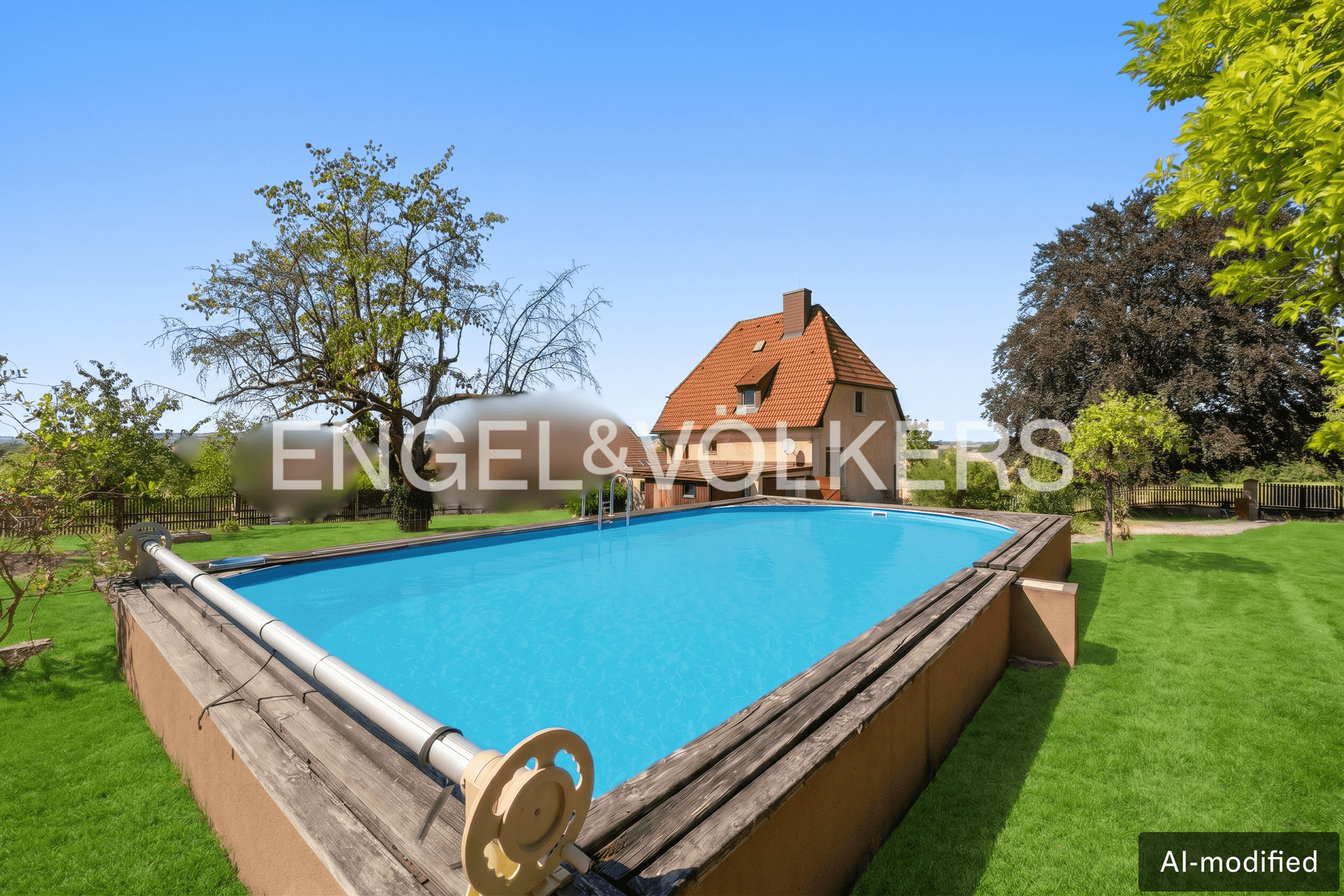 Blick auf den oberirdischen Pool im Garten mit dem Haus im Hintergrund unter blauem Himmel.
