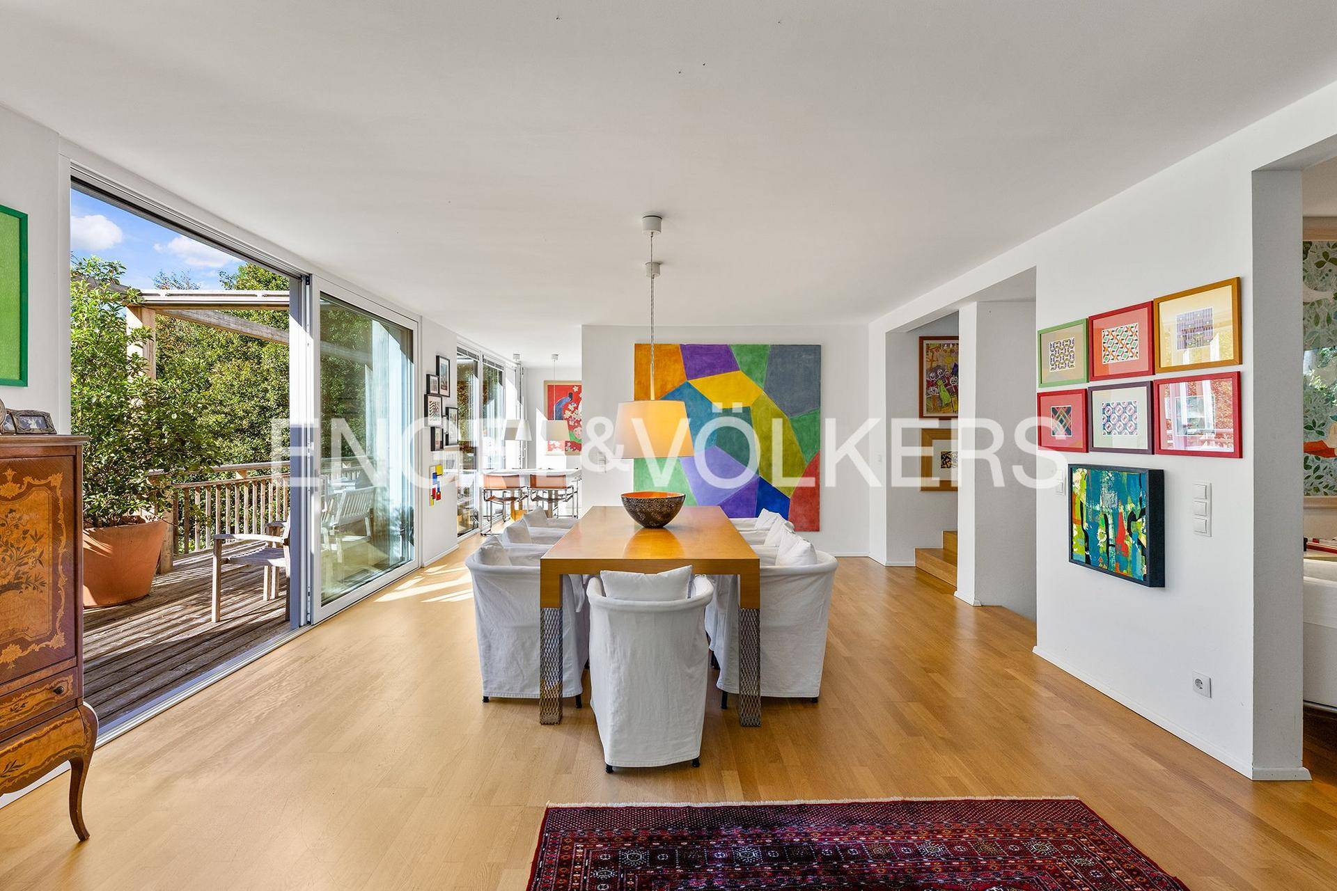 Eleganter Essbereich mit Holztisch, modernen Stühlen und farbenfroher Kunst an den Wänden.