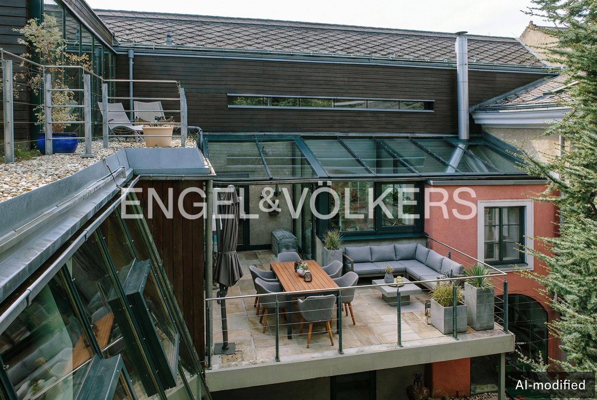 Großzügige Terrasse mit Sitzgelegenheiten und Glasdach, umgeben von grüner Vegetation.
