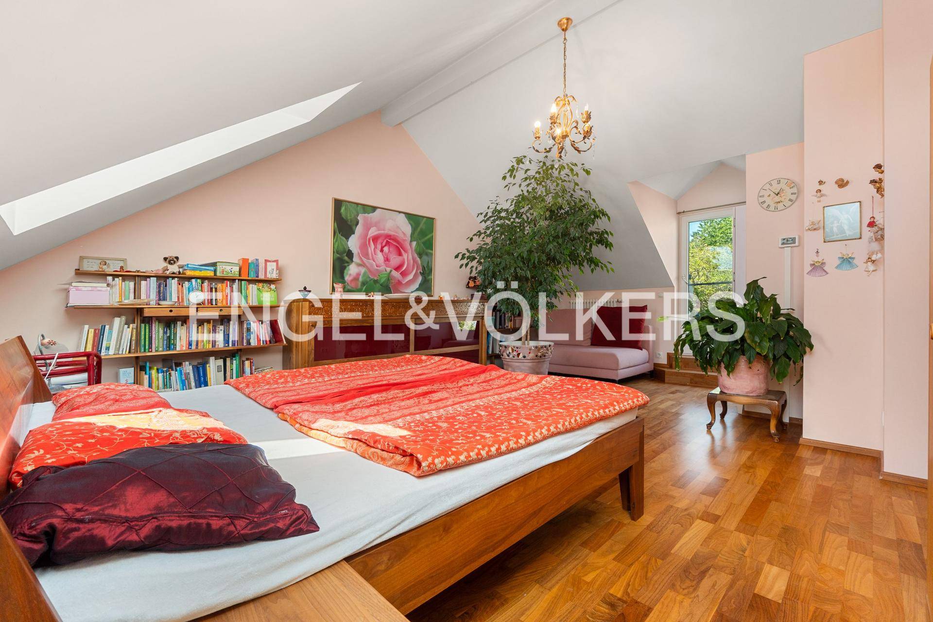 Geräumiges Schlafzimmer im Dachgeschoss mit Holzboden, Bücherregalen und schrägen Decken.
