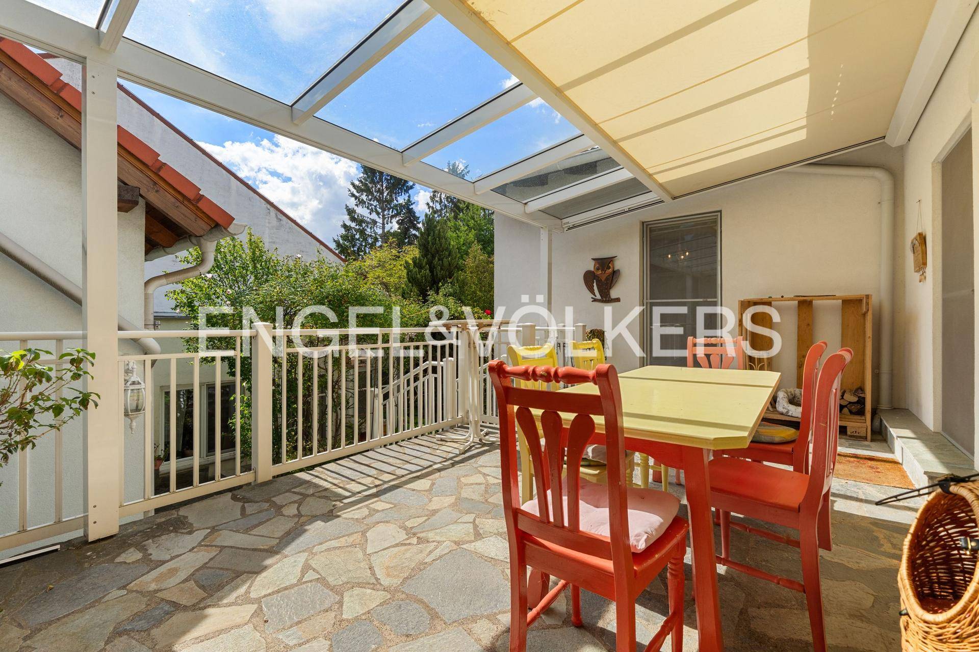 Überdachte Terrasse mit Steinboden und Gartenmöbeln, ideal für entspannte Stunden im Freien.