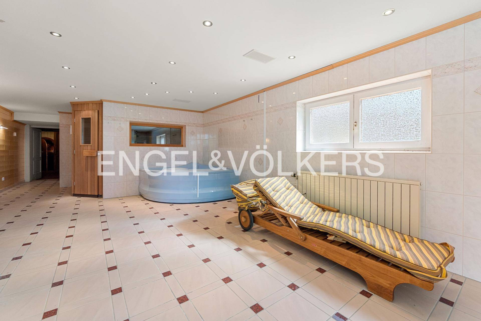 Entspannender Wellnessbereich mit Whirlpool, Sauna und Liegestuhl.