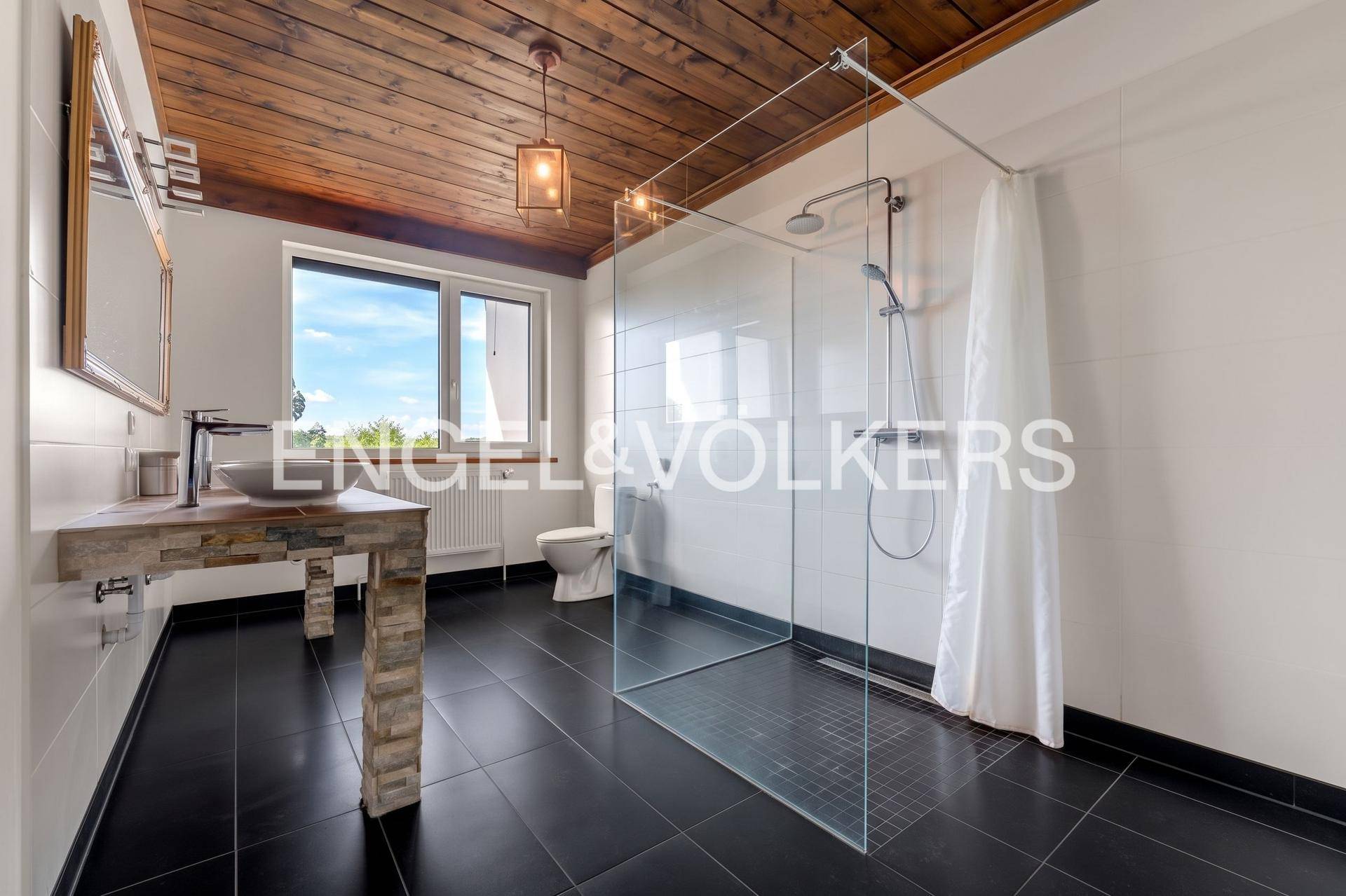 Modernes Badezimmer mit dunklen Fliesen, begehbarer Dusche und einzigartigem Waschtisch.