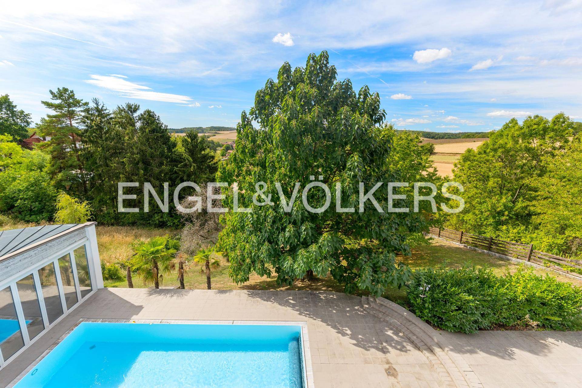 Panoramablick auf den Außenpoolbereich und die weite grüne Landschaft.