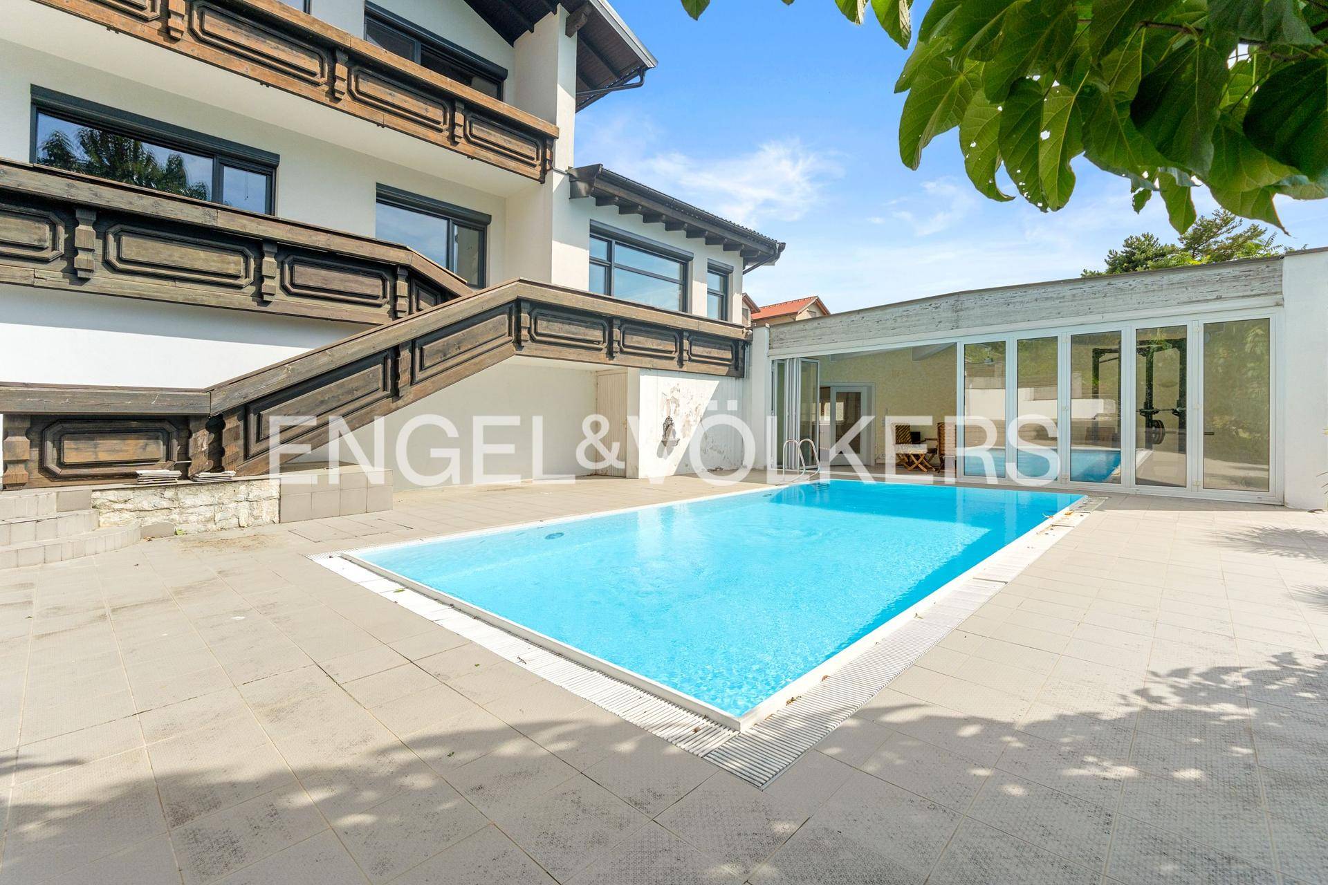 Außenbereich des Hauses mit rechteckigem Pool und angrenzendem Wintergarten.