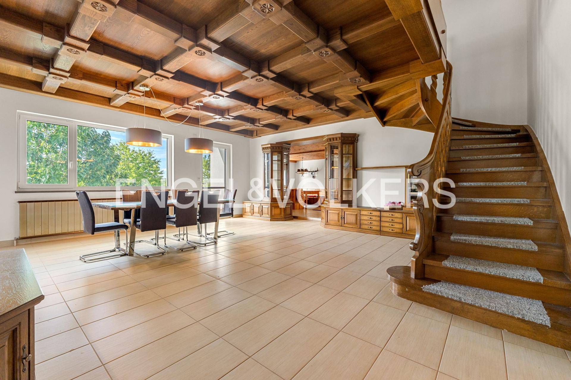 Eleganter Essbereich mit kunstvoller Holzdecke, Fliesenboden und beeindruckender Holztreppe.