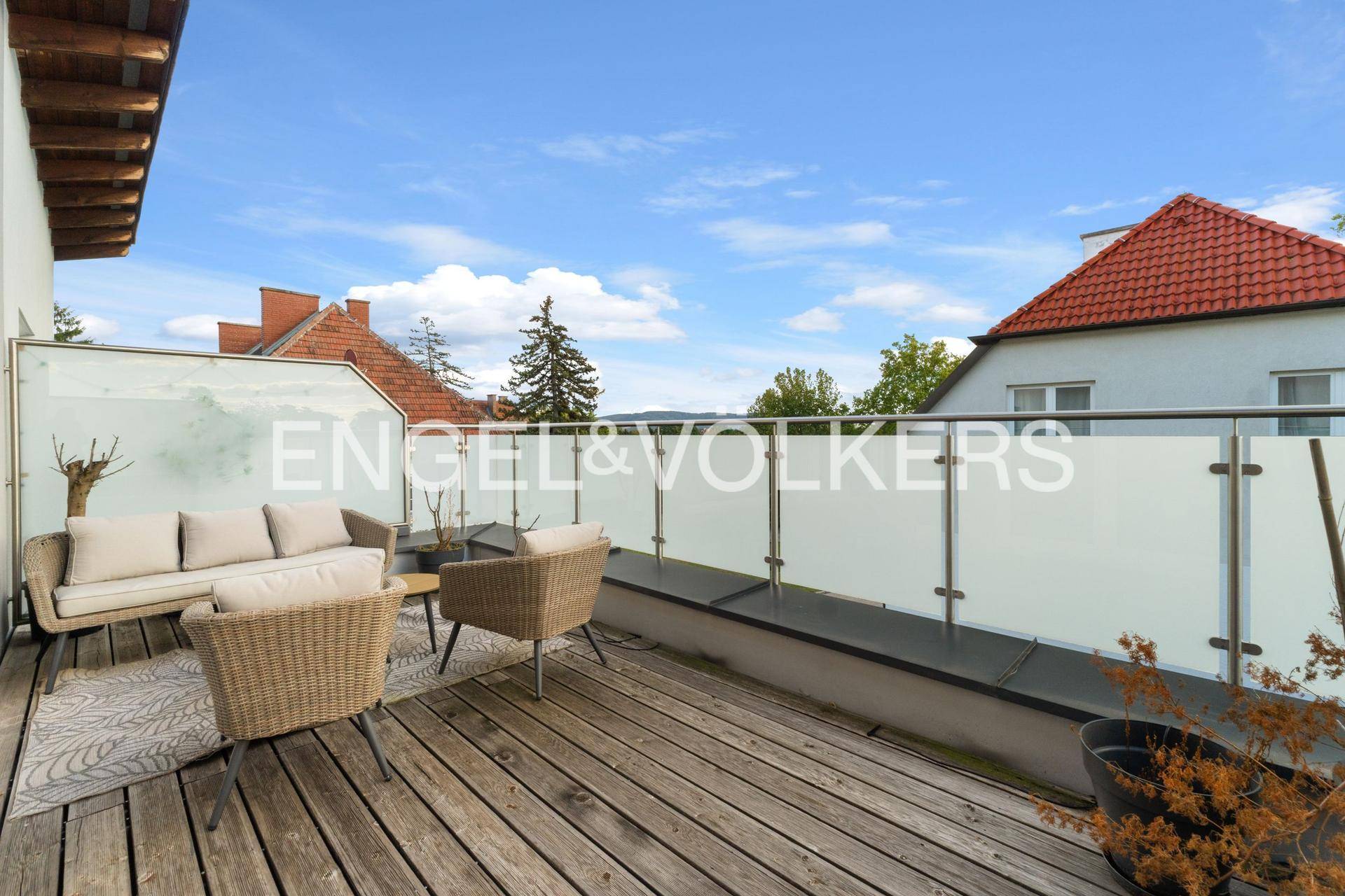 Geräumiger Balkon mit Holzbelag, Sitzgelegenheiten und weitem Ausblick.