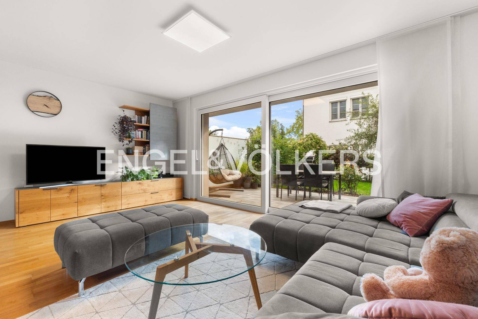 Gemütliches Wohnzimmer mit großem Sofa, TV-Möbel und Blick auf die Terrasse.