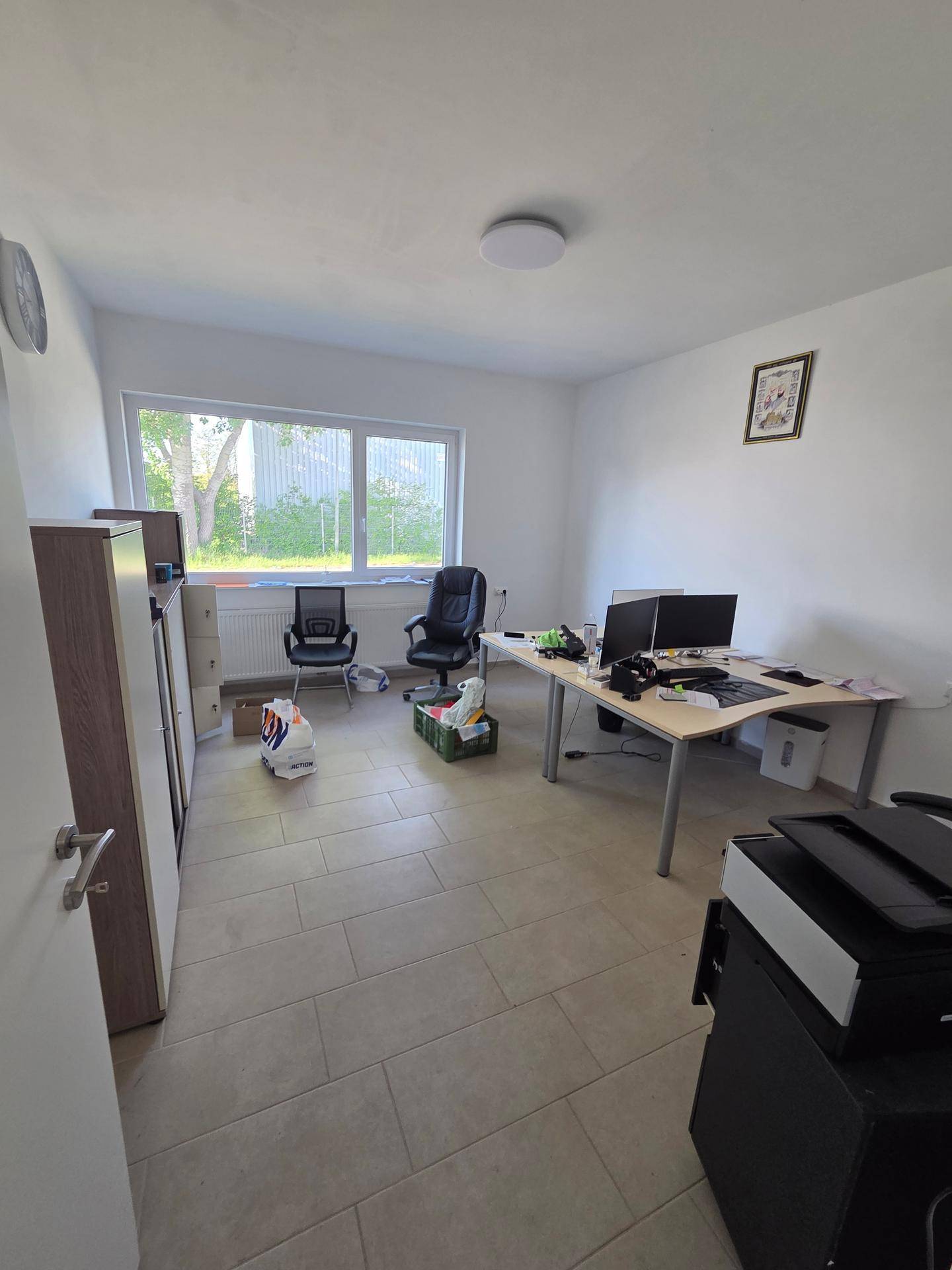 Geräumiges Büro mit mehreren Arbeitsplätzen, Computern und einem großen Fenster.