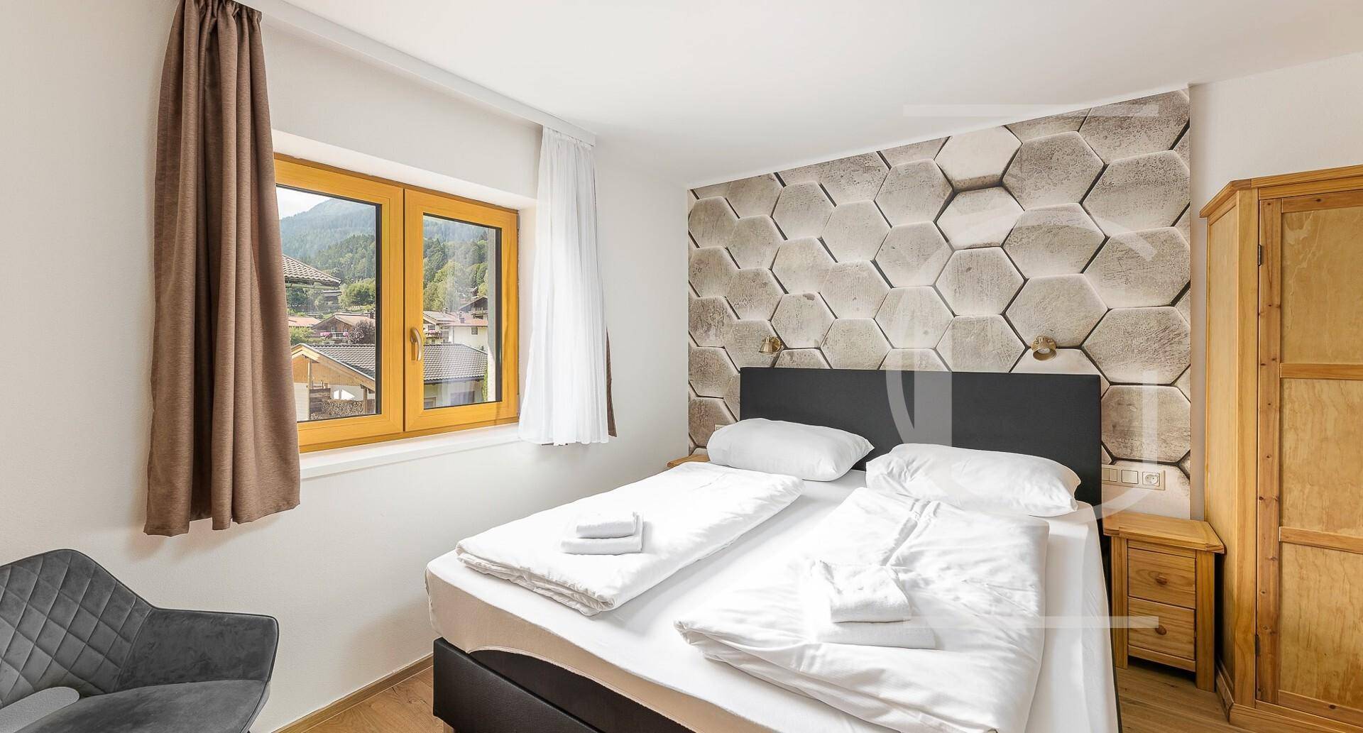 Gemütliches Schlafzimmer mit Doppelbett, Holzboden und Fenster mit Blick auf die umliegende Landschaft.