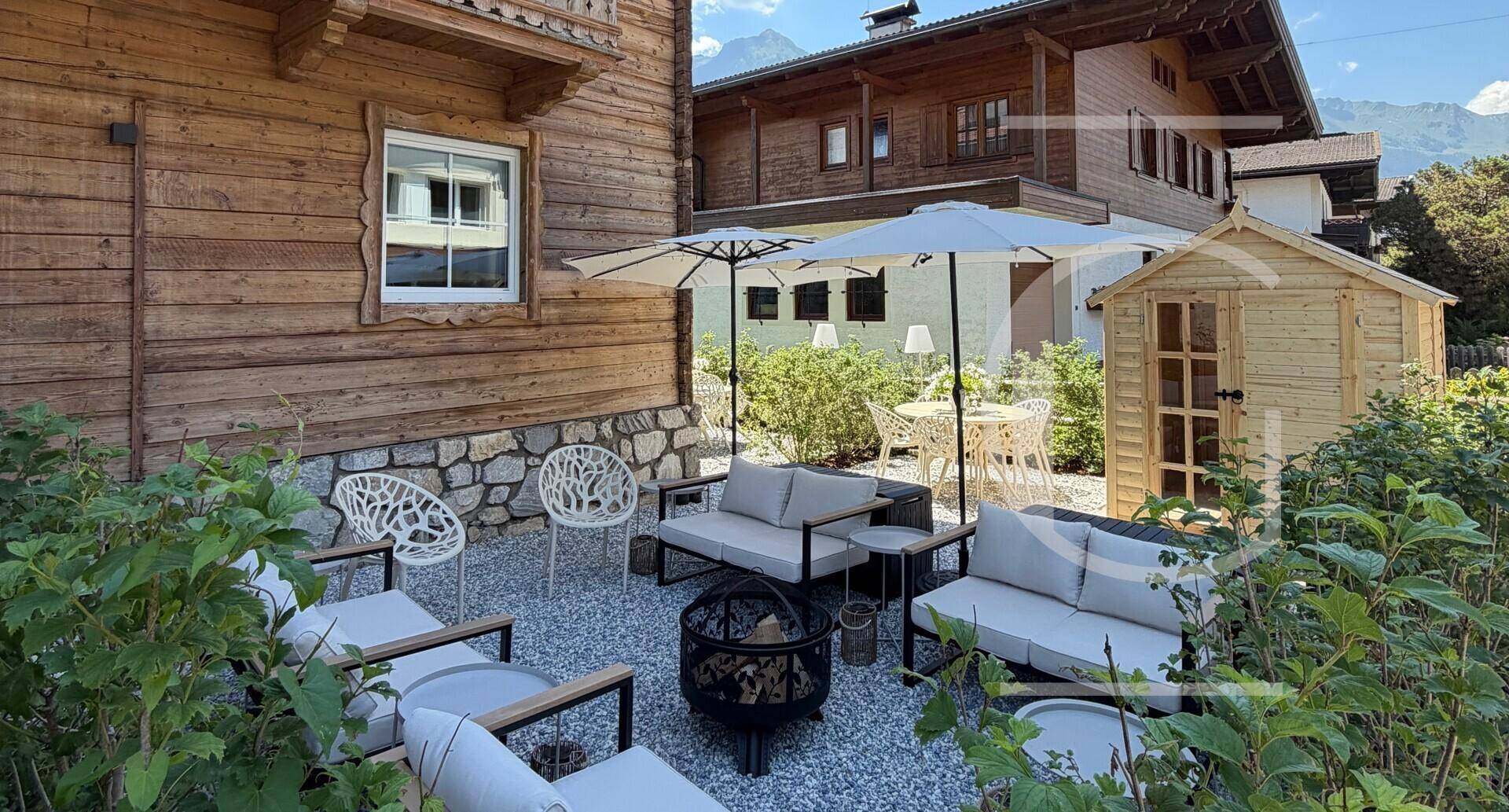 Garten mit bequemen Outdoor-Sofas, Feuerstelle und Gartenhaus.
