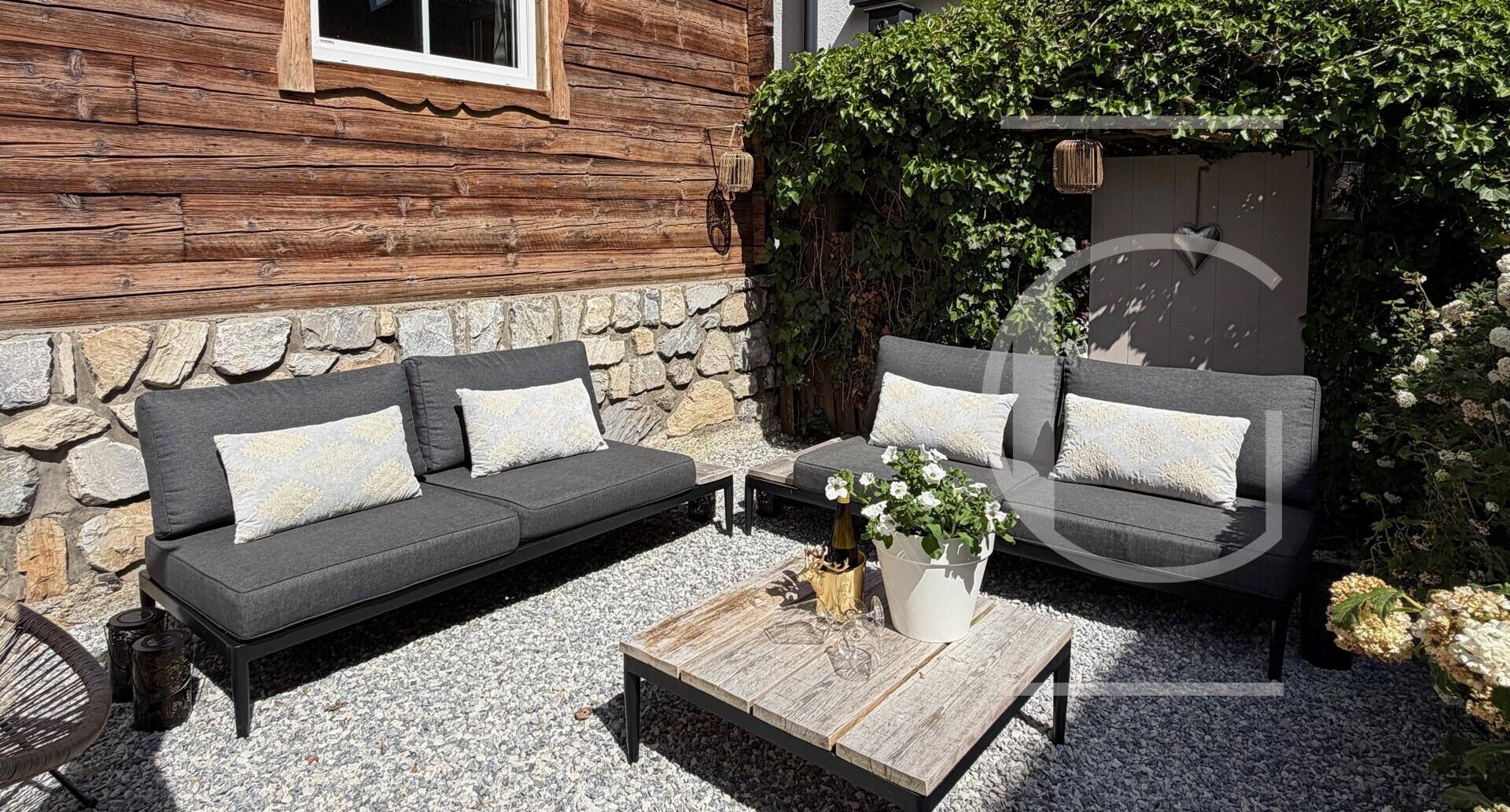 Gepflasterter Terrassenbereich mit modernen Outdoor-Sofas und Holztisch.