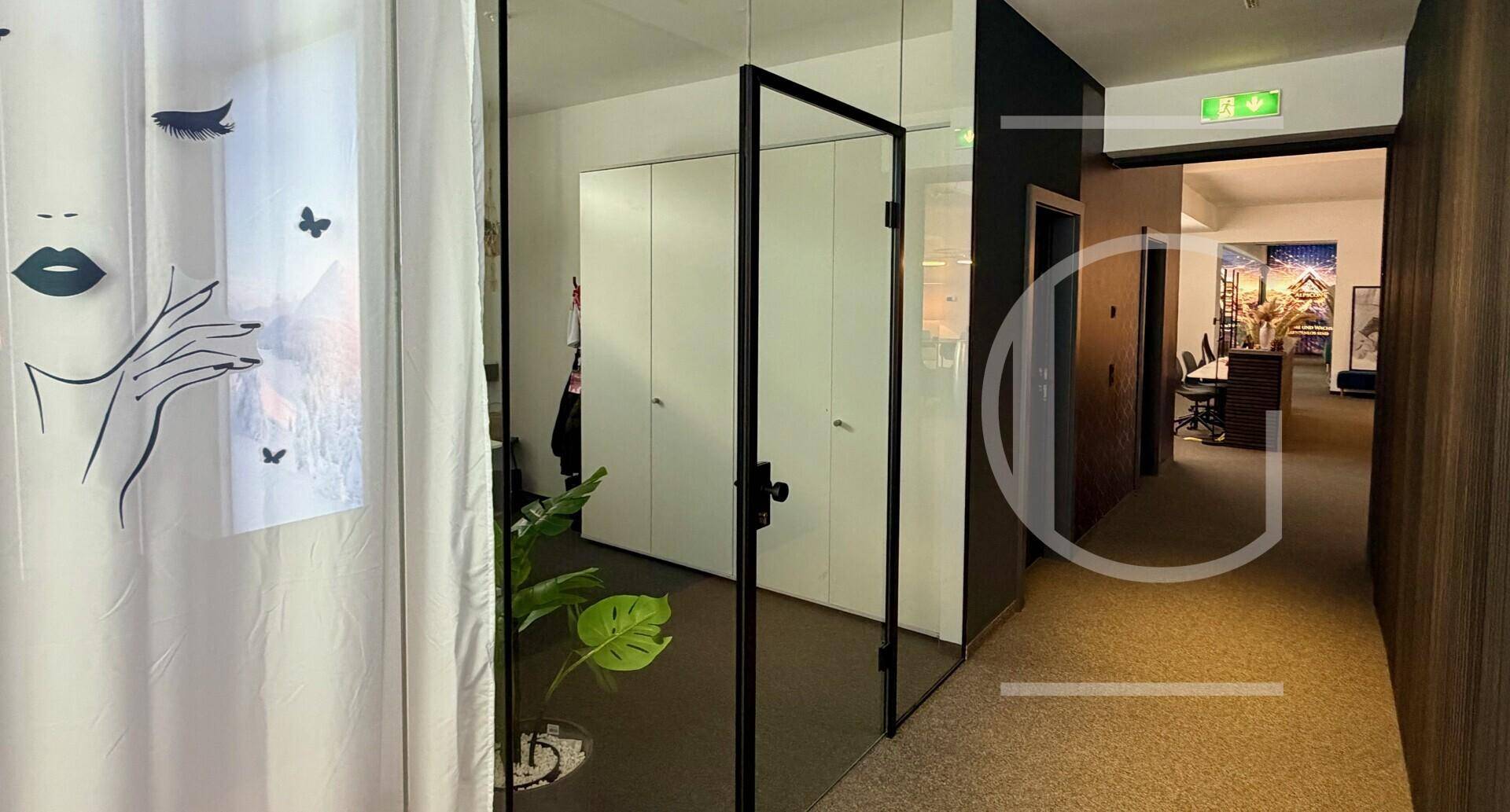 Heller Flur mit Glaswänden, weißen Schränken und Blick in einen weiteren Bürobereich.